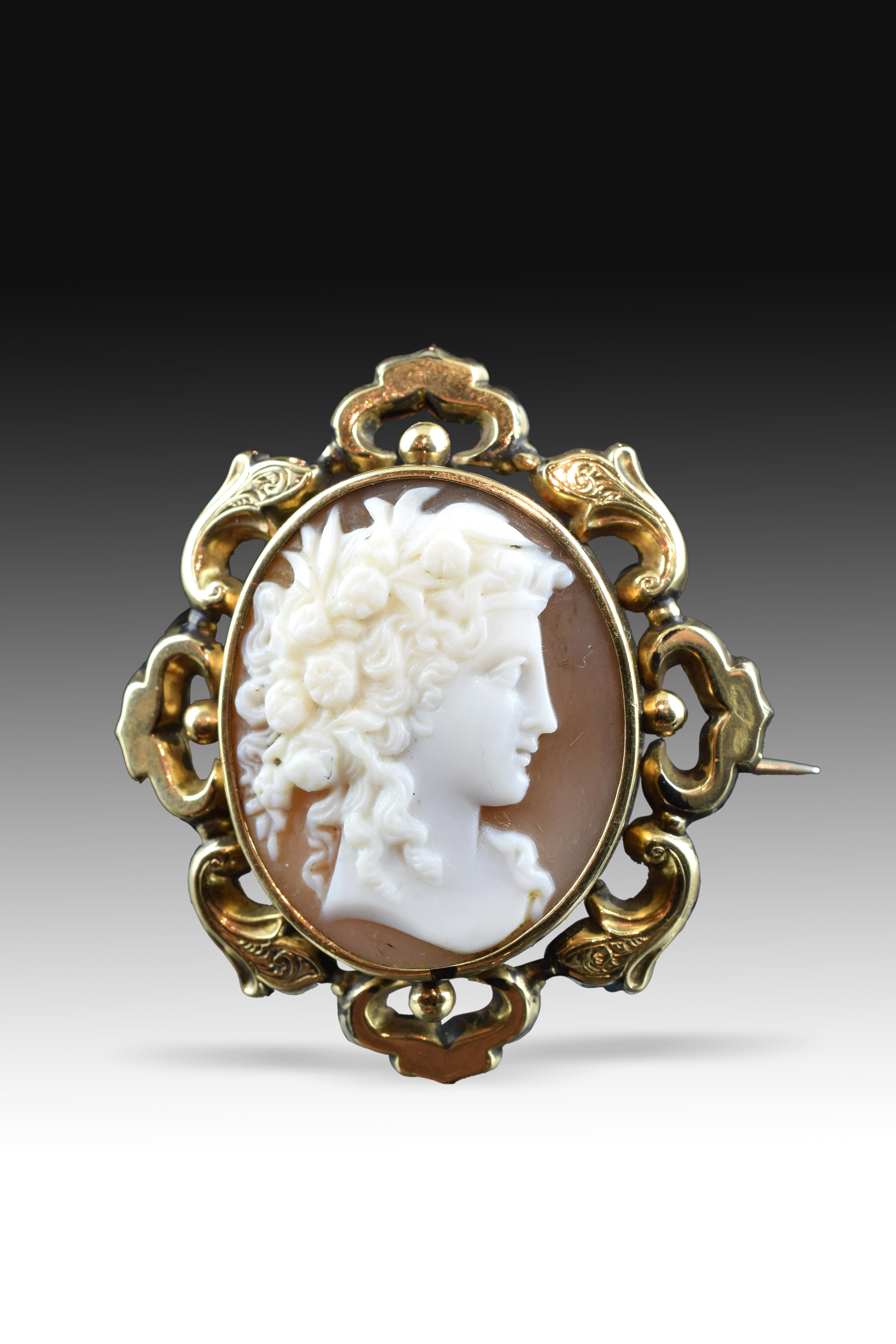 Cameo (Brosche mit Sicherheitsgriff) mit Goldrahmen. Das zentrale Stück aus Muschel (Cassius Cypraea), weiß auf Fleischton, zeigt eine weibliche Büste (in der Seitenansicht). Diese junge Dame mit ihrem reichlich mit Blumen geschmückten Haar ist