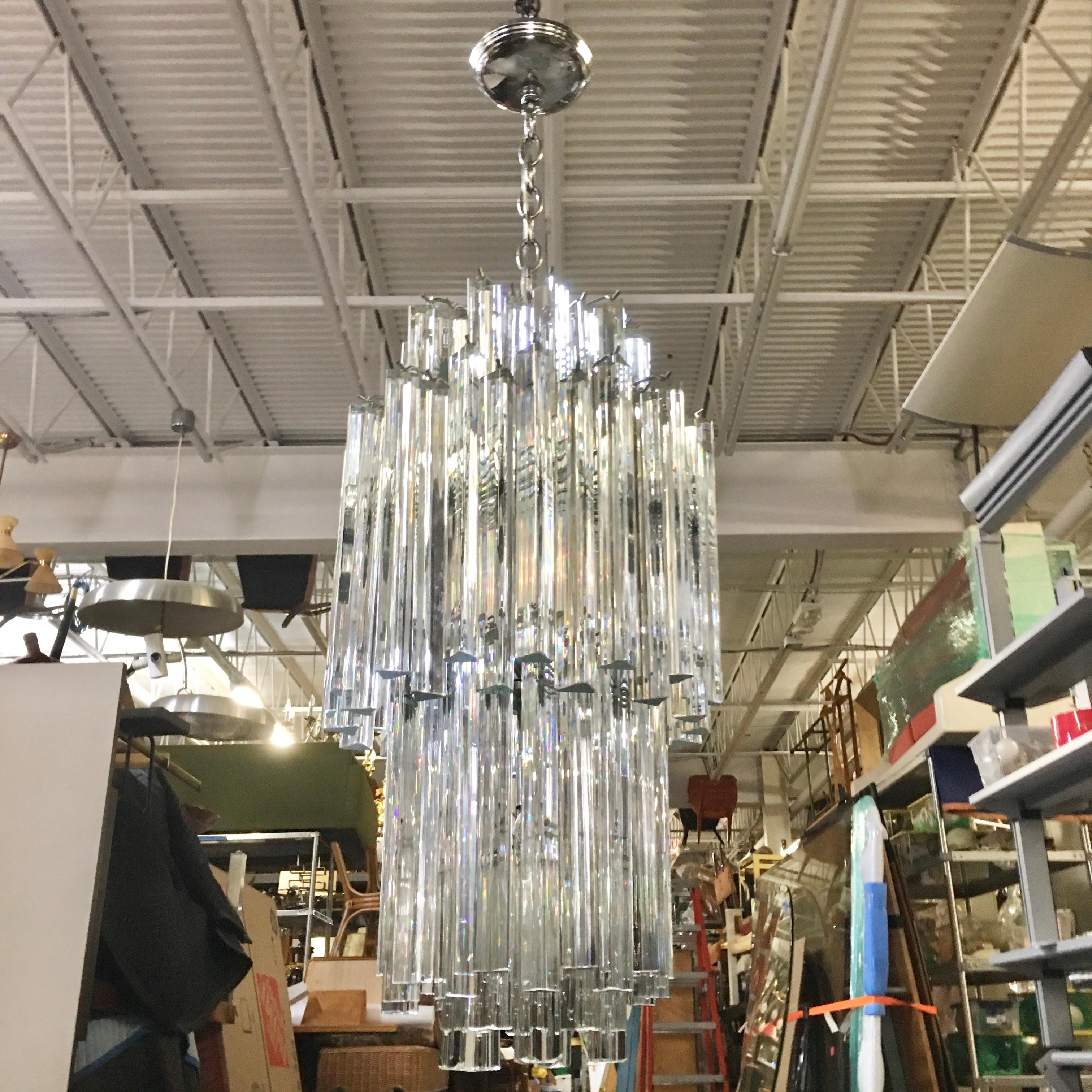 Vintage 1970s four-tier chandelier imported by Camer Glass after a design by Tony Zucchieri for Venini with crystal trilobi prisms of two different lengths (11 inches and 6 inches) hung from a round chromed steel skeletal frame.
Frame is