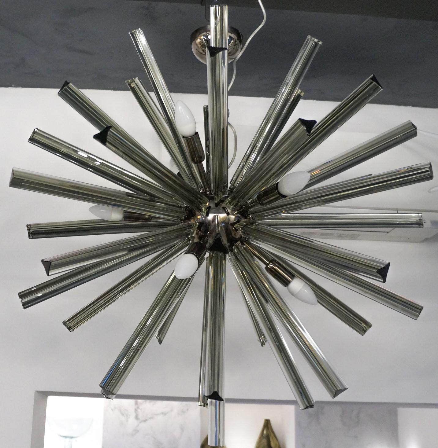 Designed in 1982 by Camer Glass, this chandelier has 43 gray glass elements called “Triedri”.
Perfect for a modern space, the chandelier reach the diameter of 80 cm and is lighted by 9 Bubs E14 that create a comfortable atmosphere lighting the