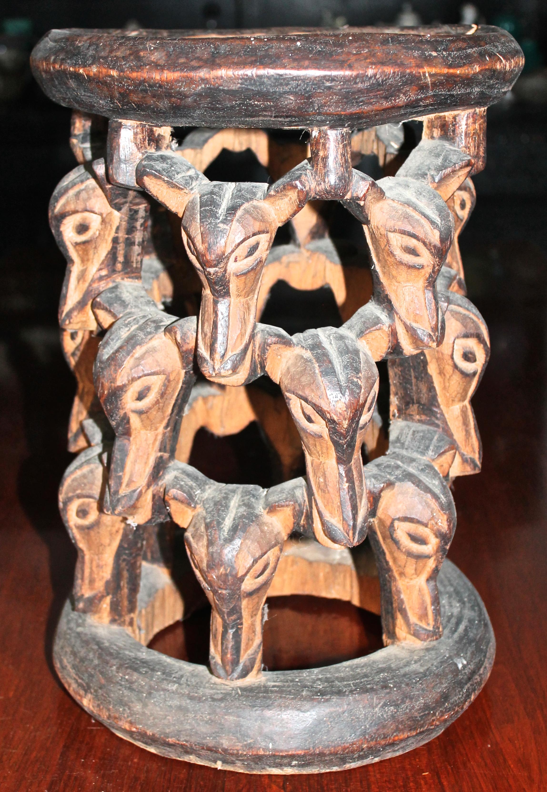 Möglicherweise Babanki.  Runder zeremonieller Holzschemel, der aus wiederholten Tierköpfen besteht. Original aufgetragene Patina.