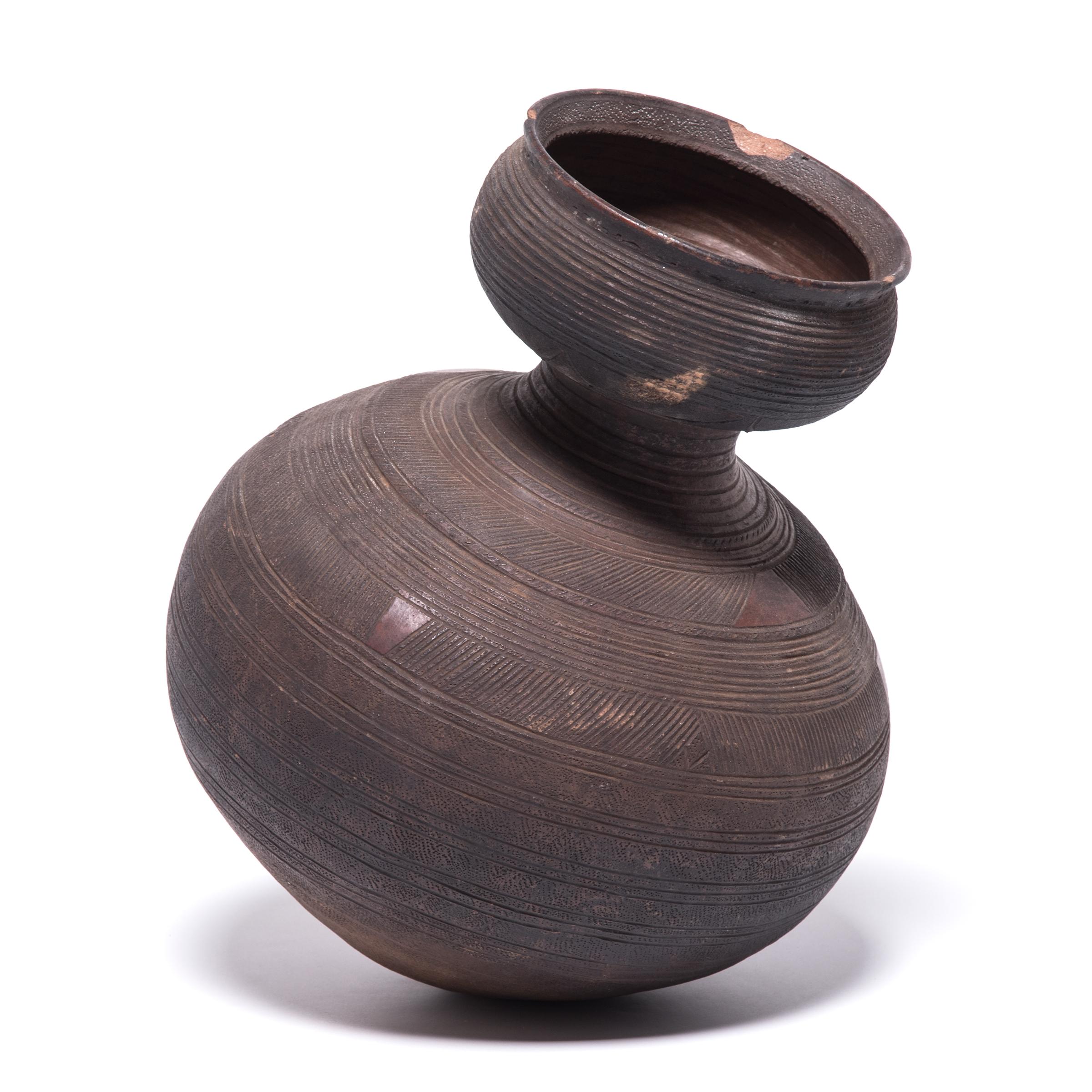 Inspired by the natural world, Nupe ceramicists fired this water vessel in the shape of a gourd. The vessel's varied textures and colors come from its functional design. The dimpling and geometric markings were engraved to give the drinker a better