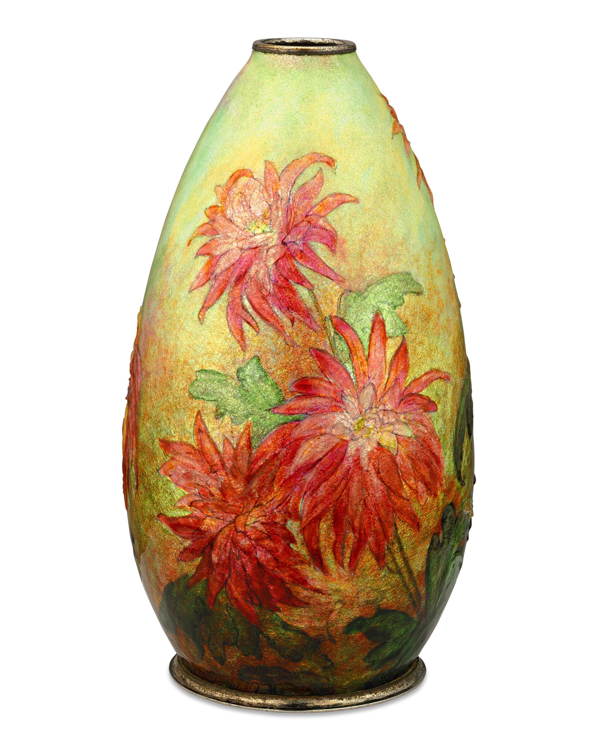 De délicates fleurs de chrysanthèmes orange s'épanouissent dans ce vase émaillé de Camille Fauré. Réalisée selon la technique qui a fait sa renommée, la forme en cuivre du vase est recouverte de feuilles d'argent et d'émail richement coloré qui