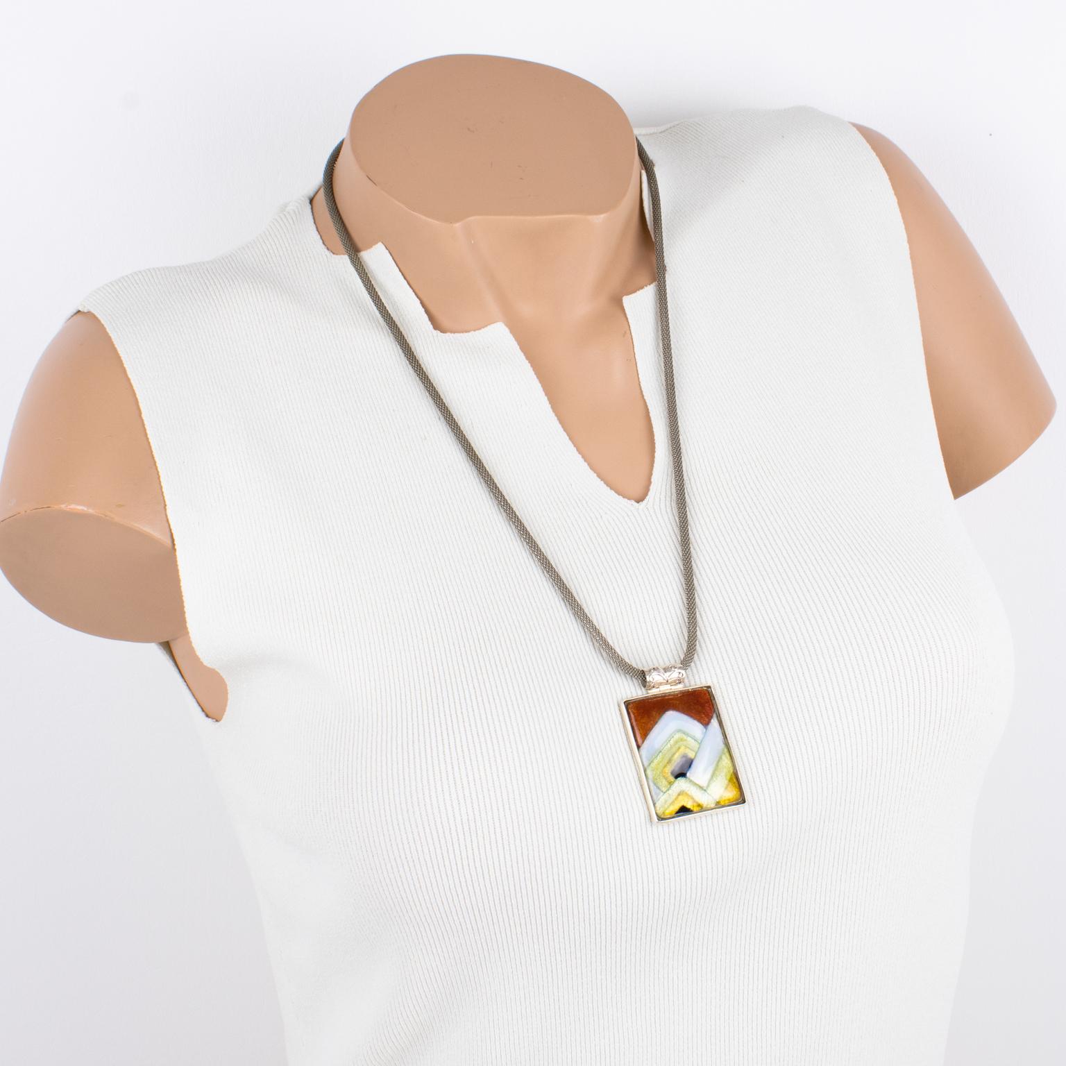This elegant pendant necklace was hand-crafted by Limoges enamelist artist Mauricette Pinoteau. The rectangular silver plate frame is ornate with an enamel-on-copper cameo. The Art-Deco-inspired design has a geometric shape. The pendant boasts
