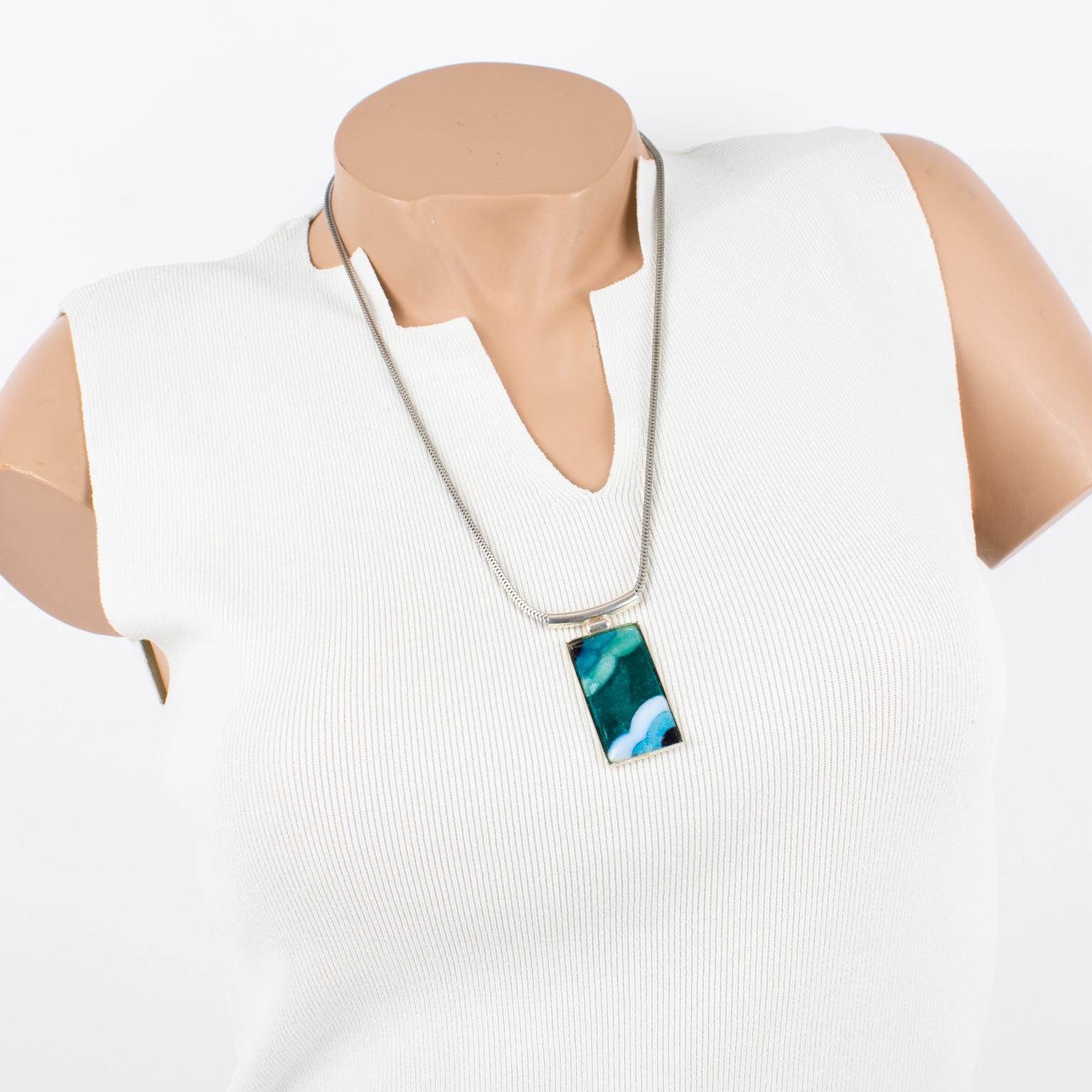This gorgeous pendant necklace was hand-crafted by Limoges enamelist artist Mauricette Pinoteau. The rectangular silver plate frame is ornate with an enamel-on-copper cameo. The Art Deco-inspired design features a geometric shape. The pendant