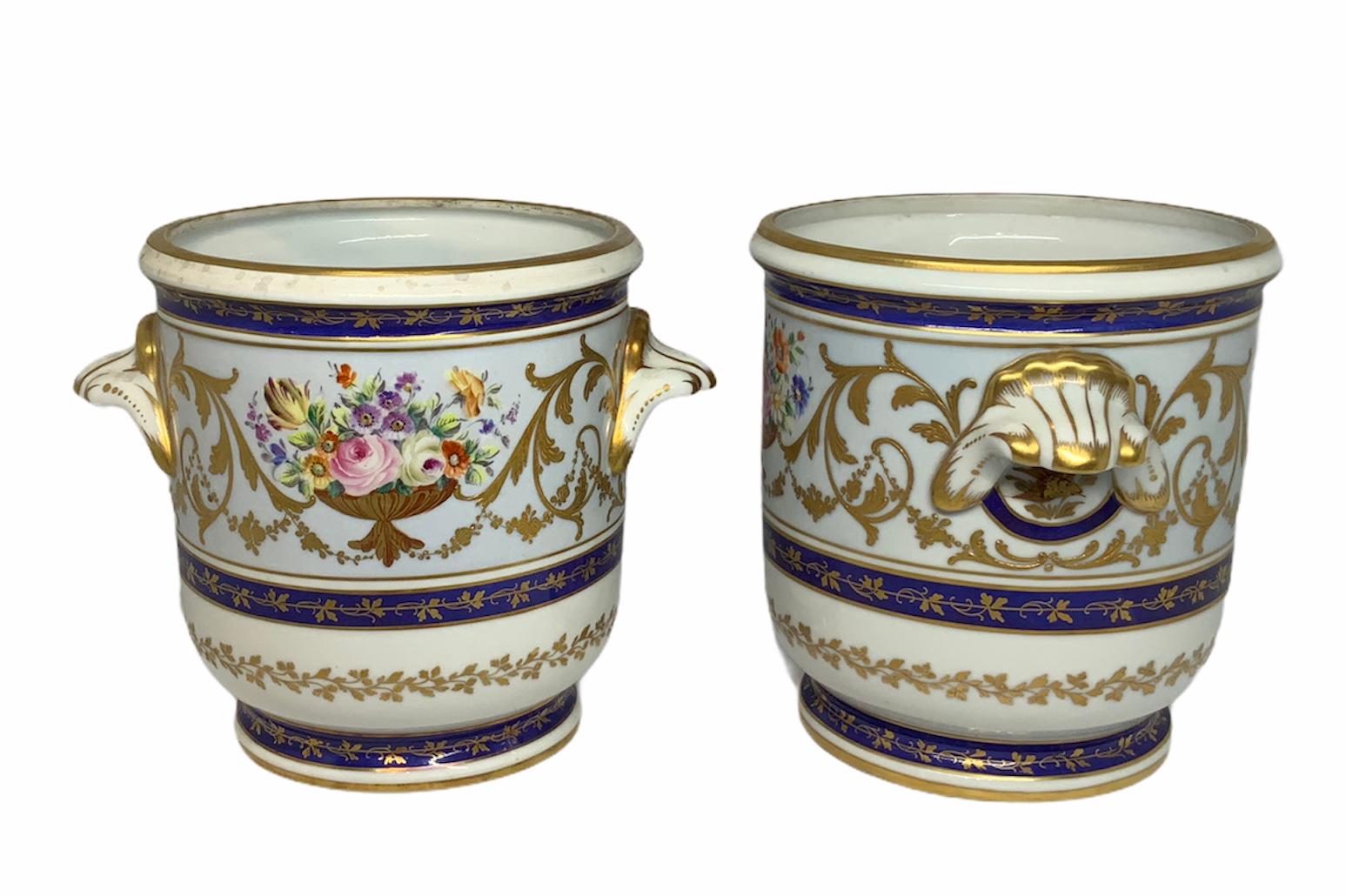 This a set of hand painted Porcelain cachepots depicting a decoration in a gilded centerpiece of a flower arrangement in the front and gilt acanthus growing along the diameter sides of it . Also, there are three hand painted cobalt blue rings around