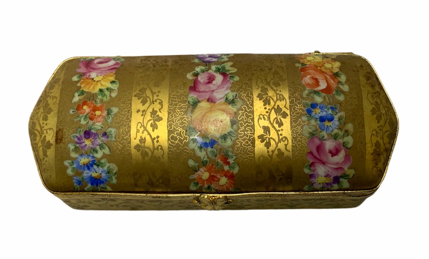 Dies ist eine vergoldete, handbemalte, längliche Scharnierbox. Sie ist mit einer Blumengirlande und einer Girlande aus Petersilienzweigen geschmückt. Auf der Innenseite des Deckels ist eine einzelne handgemalte Rose zu sehen. Diese Box eignet sich