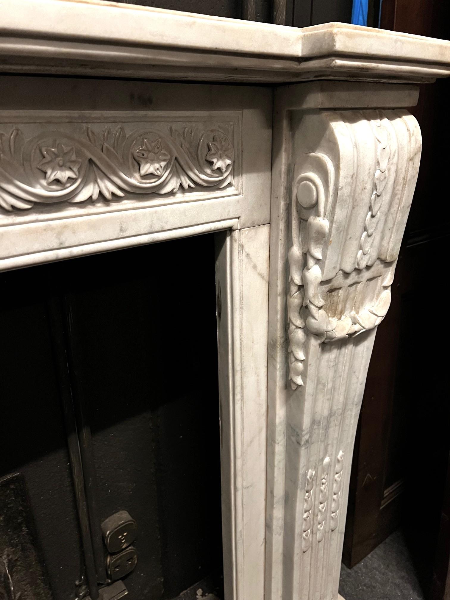 Camino en marmo bianco Carrara, fronte scolpito con motivo di fiori susseguenti Mármol de Carrara en venta