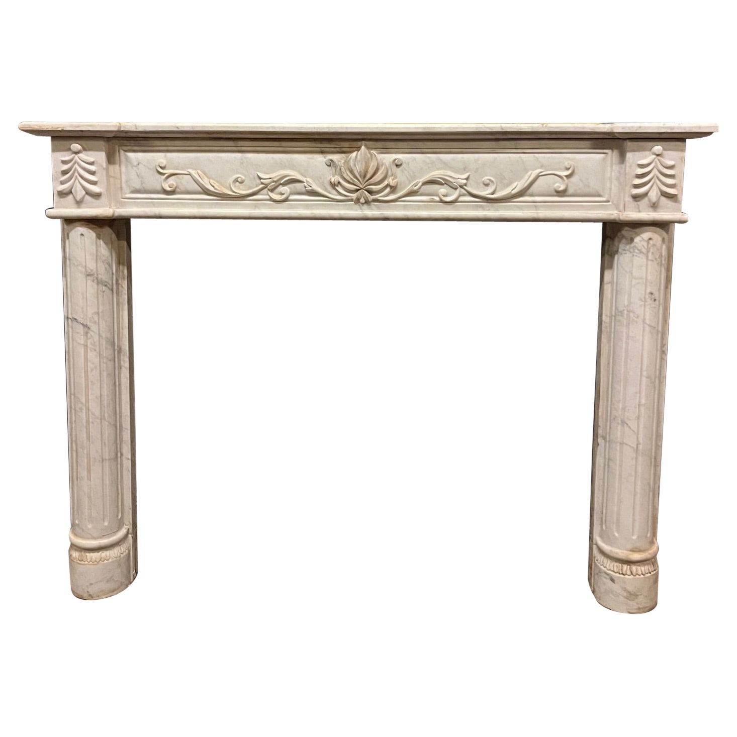 Camino in marmo bianco con venature grigie, scolpito con semicolonne e fregi