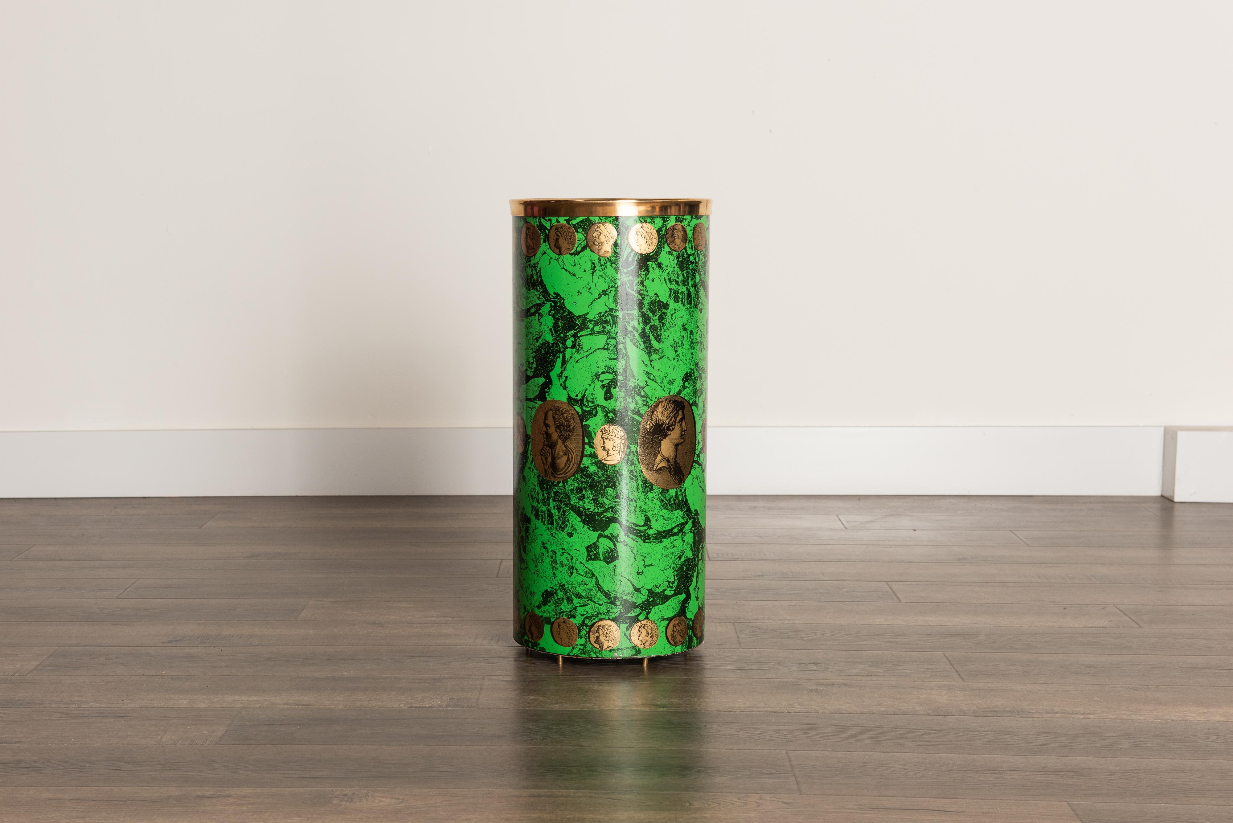 This rare and coveted collectors item is the 'Cammei' umbrella stand by Piero Fornasetti, circa 1960s, signed underneath. This hefty round umbrella bin is made with lithographic transfer and lacquered metal that has gold Roman style coin cameos over