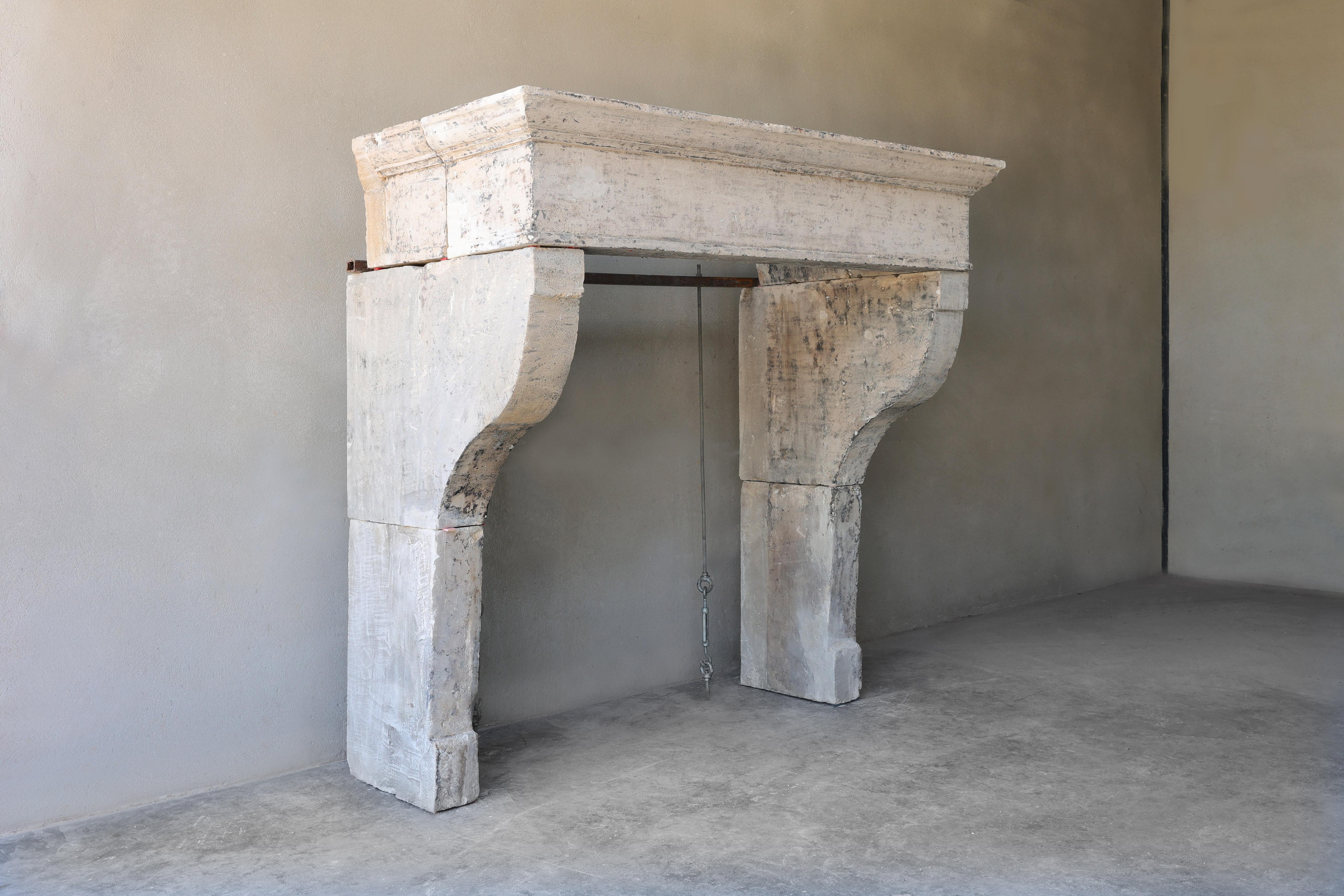 Rustic antique fireplace of French limestone in Campagnarde style. This mantelpiece has a nice wide front part and slightly curved legs. A fireplace with a nostalgic look and dimensions that can be used for many interiors!