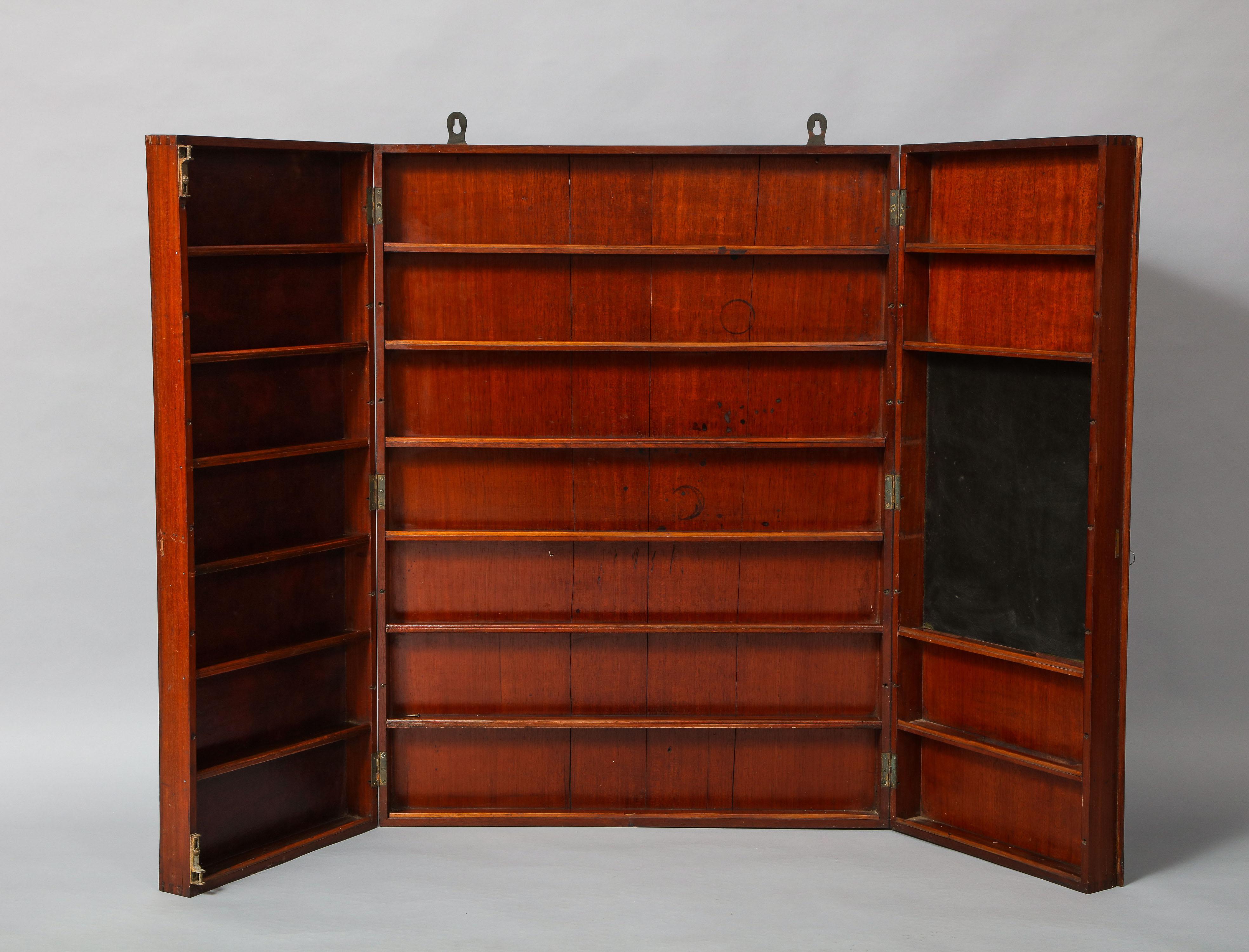 Rare Georgian mahogany campaign apothecary shelf/cabinet having two doors with half round molded edges, opening to reveal rows of fixed shelves and the right side additionally fitted with writing/mixing surface (presumably for use when not hanging!)