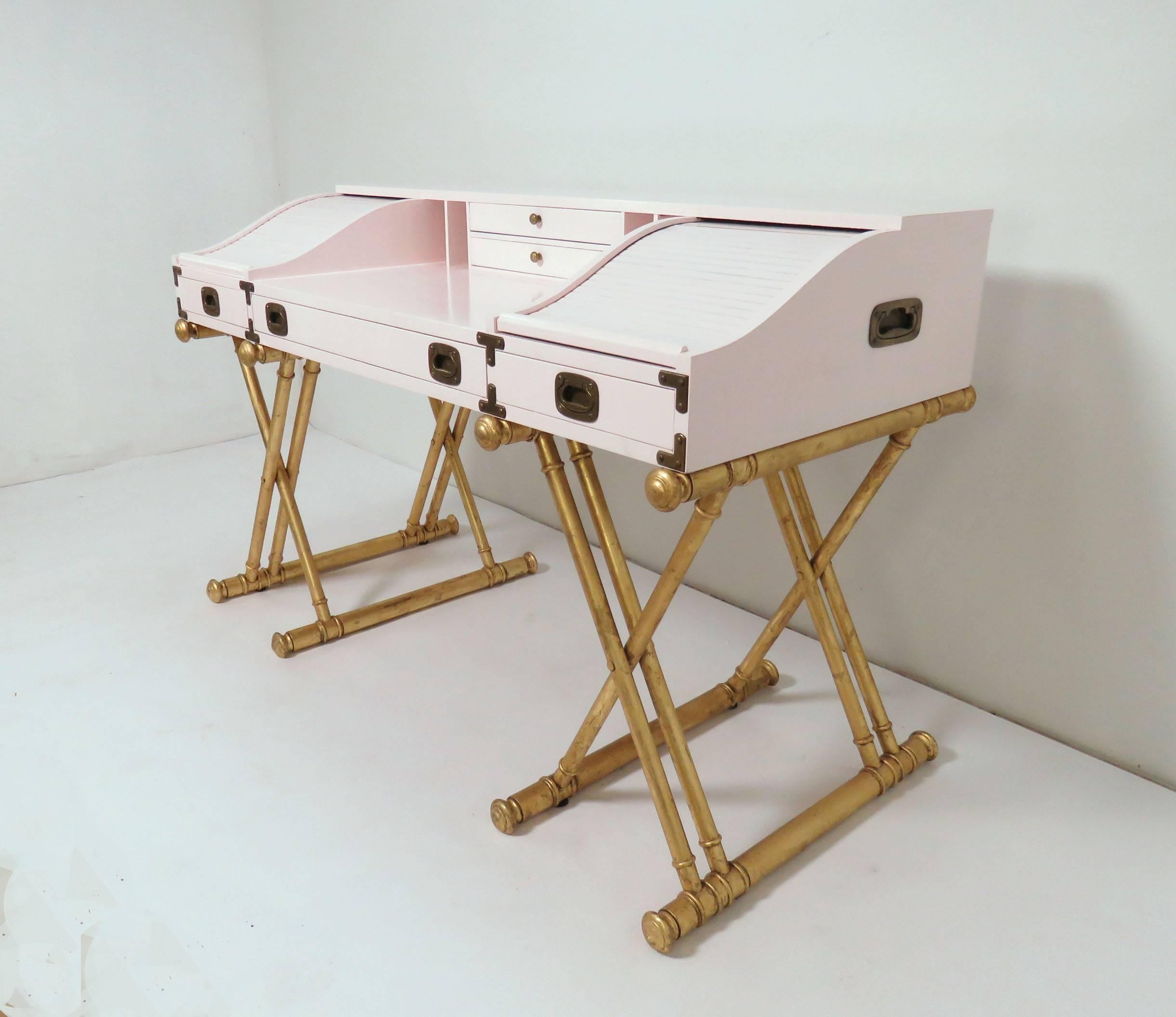 Campaign desk with roll top side elements, finished in a pale shade of pastel pink, on giltwood X-form legs by Drexel Furniture Co., circa 1970s. 

Overall desk height 34.5