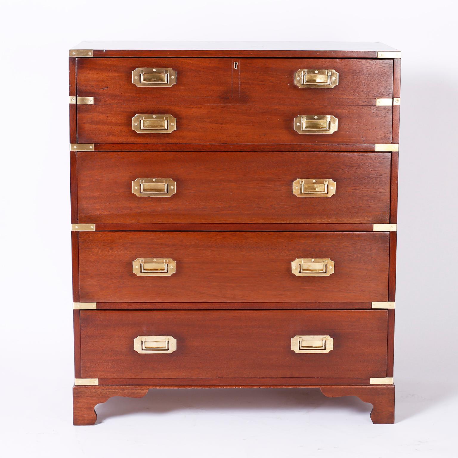 Handsome antique English campaign chest featuring a pull out tan leather secretary or desk in the top drawer and four drawers below, brass hardware and classic bracket feet.