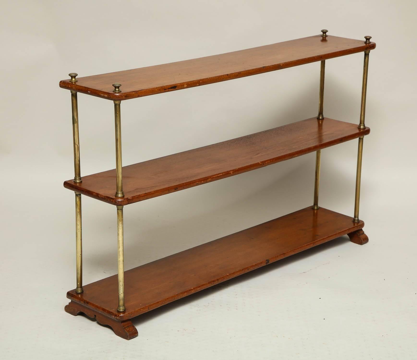 English 19th century brass and mahogany three tier campaign bookshelf standing on scalloped shoe feet, having good mellow color.  Disassembles for traveling.