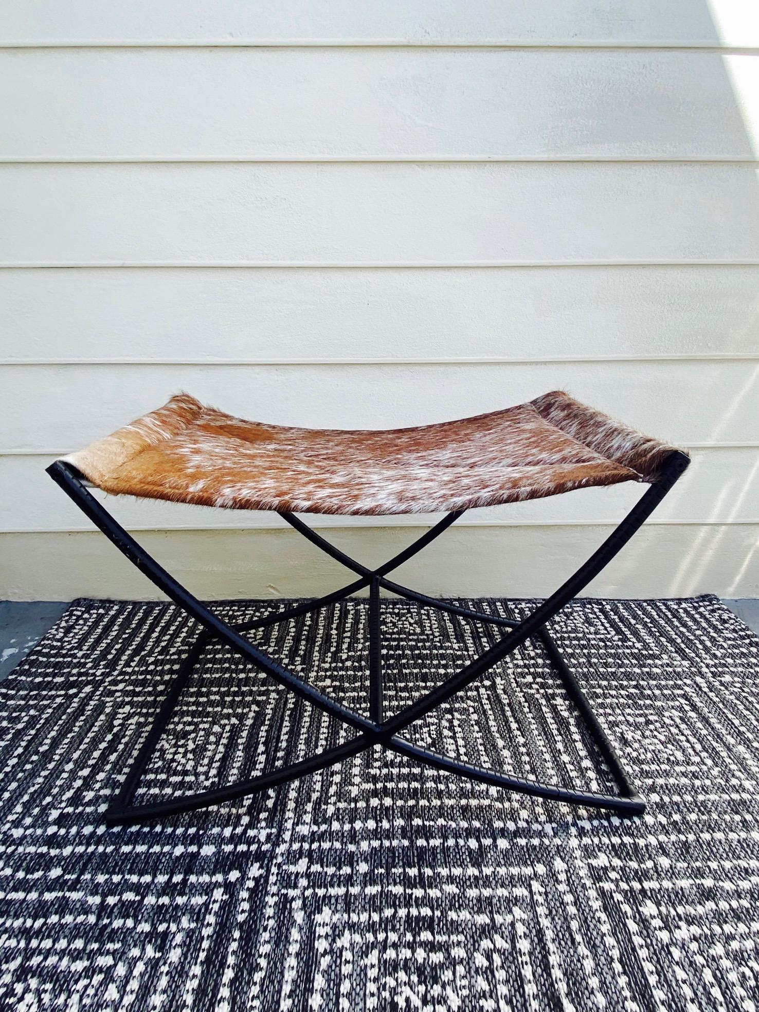 Genuine cowhide leather bench or stool features a handcrafted sling seat with quilted diamond pattern in cognac brown and white. The stool has a Campaign Era design featuring a black wrought iron X- frame with incised grooves and with a center
