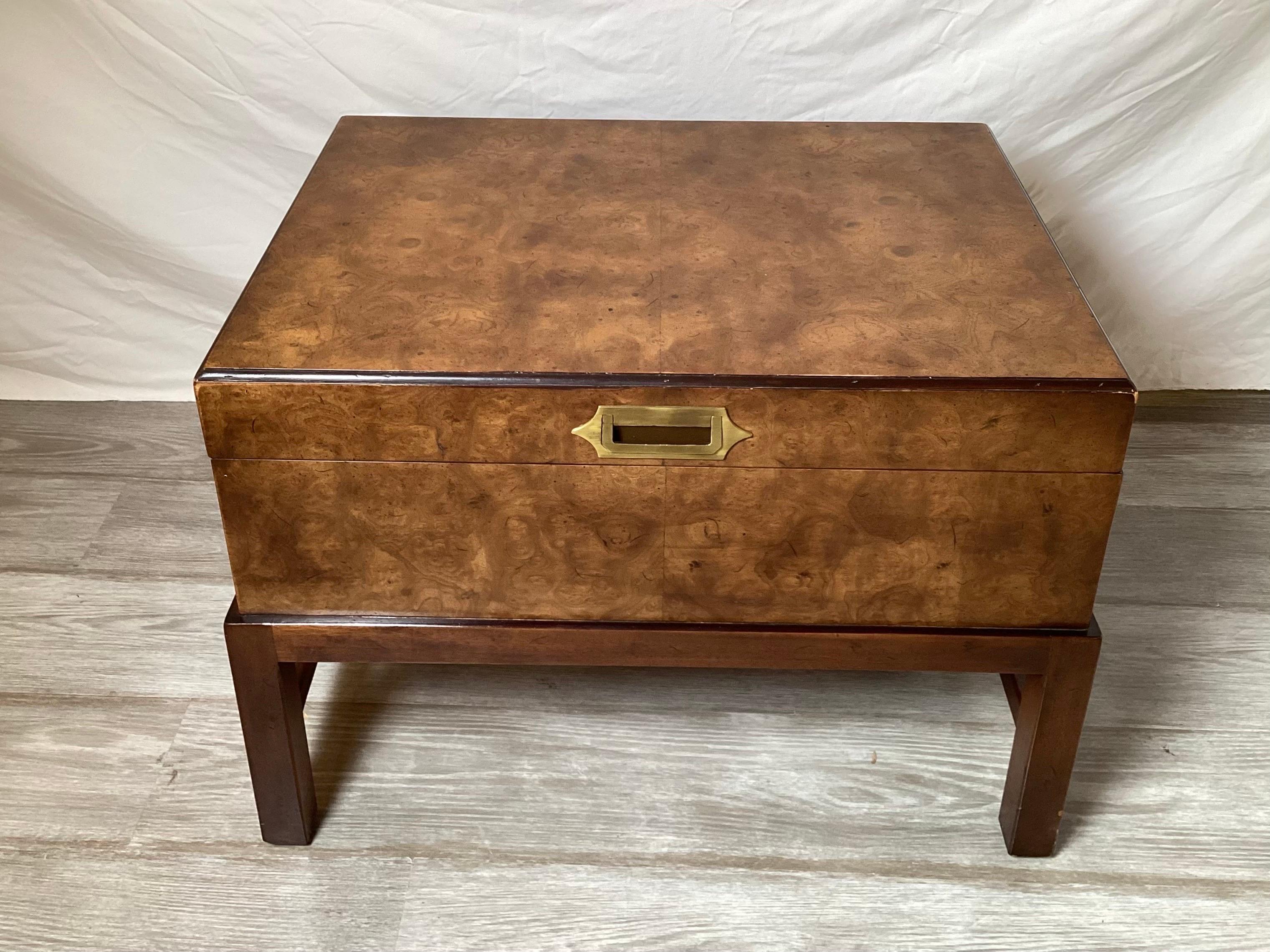 A 1970's burl walnut campaign style box on attached stand. The burl walnut box with recessed brass handle at the front with a parson style solid mahogany base. A great small coffee table or side chest in a medium tone wood and dark at the base.