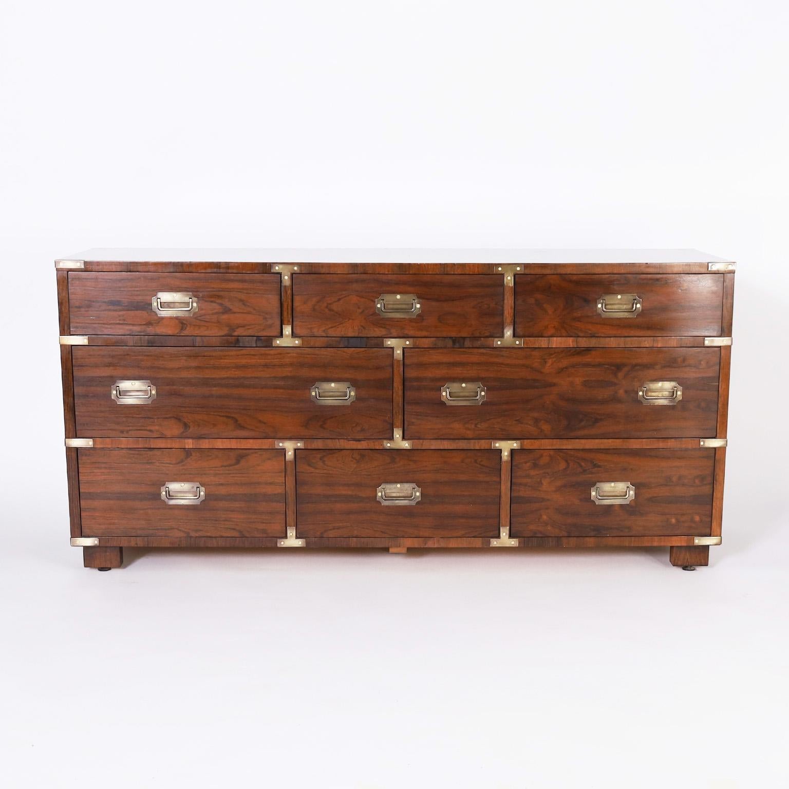 Handsome vintage campaign style chest with eight drawers crafted in rosewood with bold grains and cross banding on the front, brass hardware, and block feet. Perfect marriage of traditional and modern. Signed Dimension in a drawer.