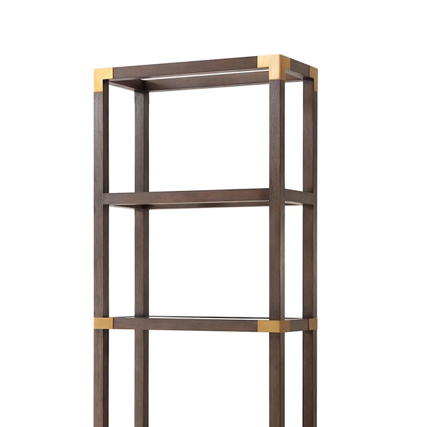 A campaign-style Beech etagere with glass inset shelves. This etagere is crafted of solid textured Beech with a cardamon finish and is accented with brushed brass-finished corners. 

Dimensions: 32