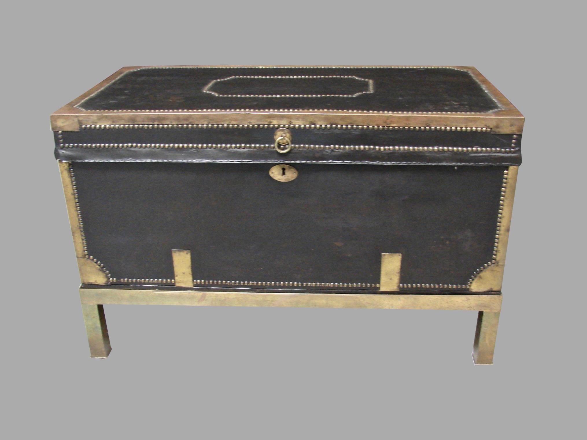 An English campaign style leather and brass mounted trunk, decorated overall with brass banding bordered by nailhead trim, the interior later lined in cut velvet now resting on a custom brass stand of a later date. Possibly of Chinese export origin.