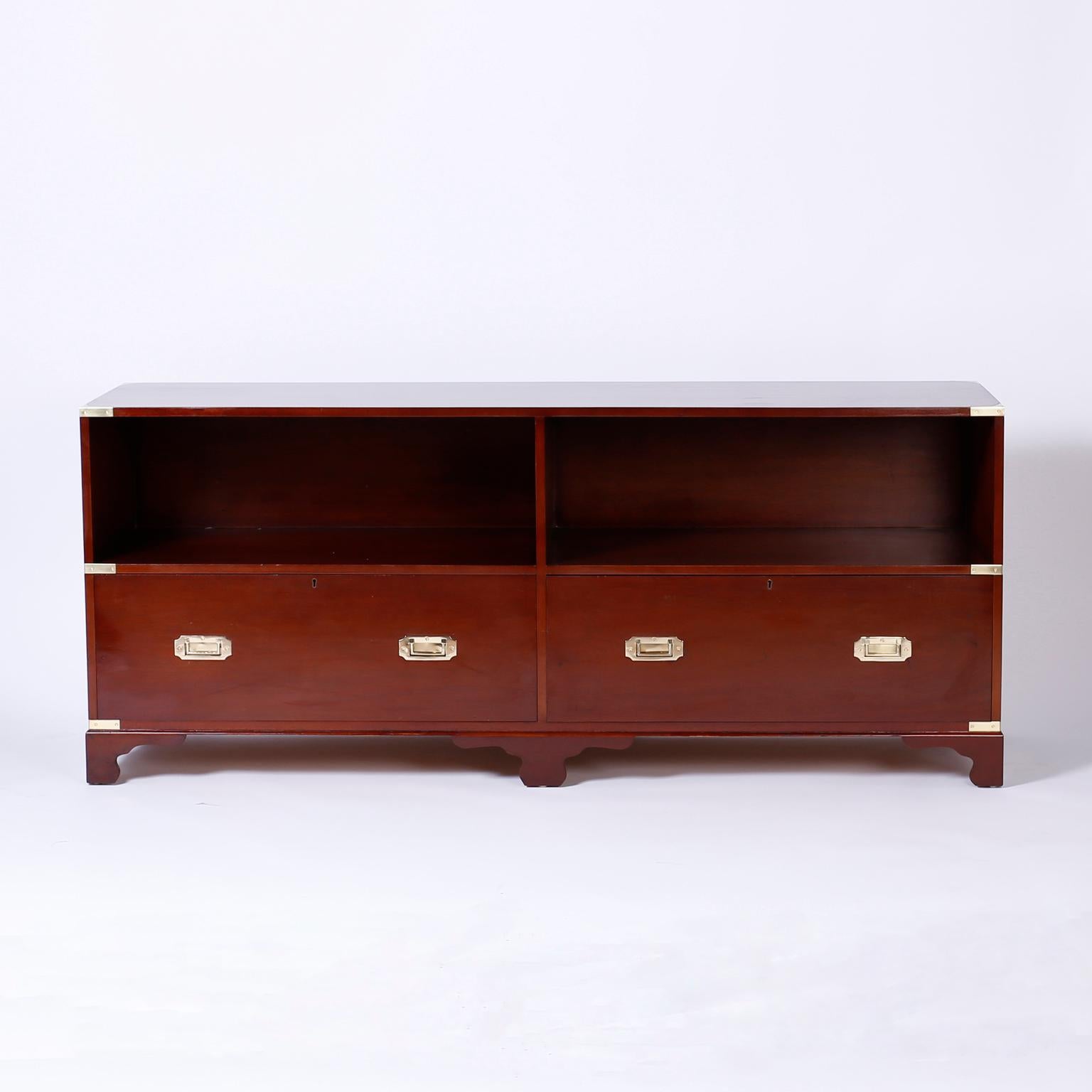 Unusual campaign style mahogany console with book or storage space over two lateral file drawers, brass hardware, long sleek form, and classic bracket feet. Perfect for an office or library.