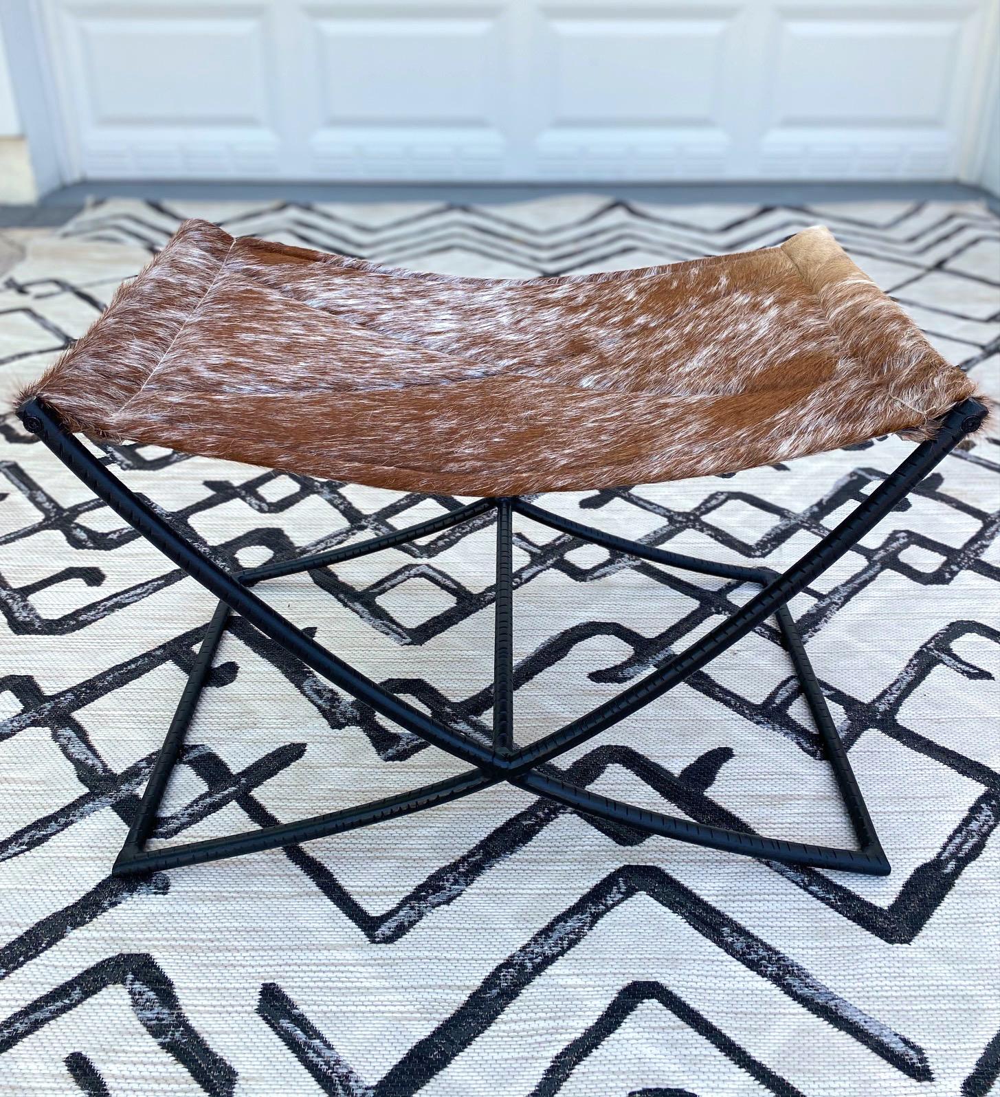 Genuine cowhide leather bench features a handcrafted sling seat with quilted diamond pattern. The stool has a Campaign Era design featuring a black wrought iron X- frame with incised grooves and with a center reinforcement bar. Makes a great accent