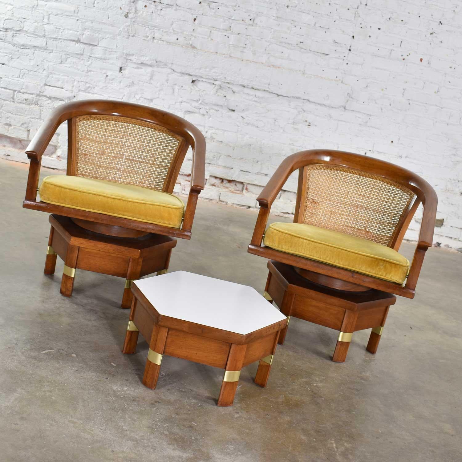 Handsome and unusual pair of campaign style swivel chairs with a cane back and loose seat cushion on a hexagon base. They are combined with a low hex table with white laminate top. All are by Hickory Furniture Manufacturing. They are in wonderful