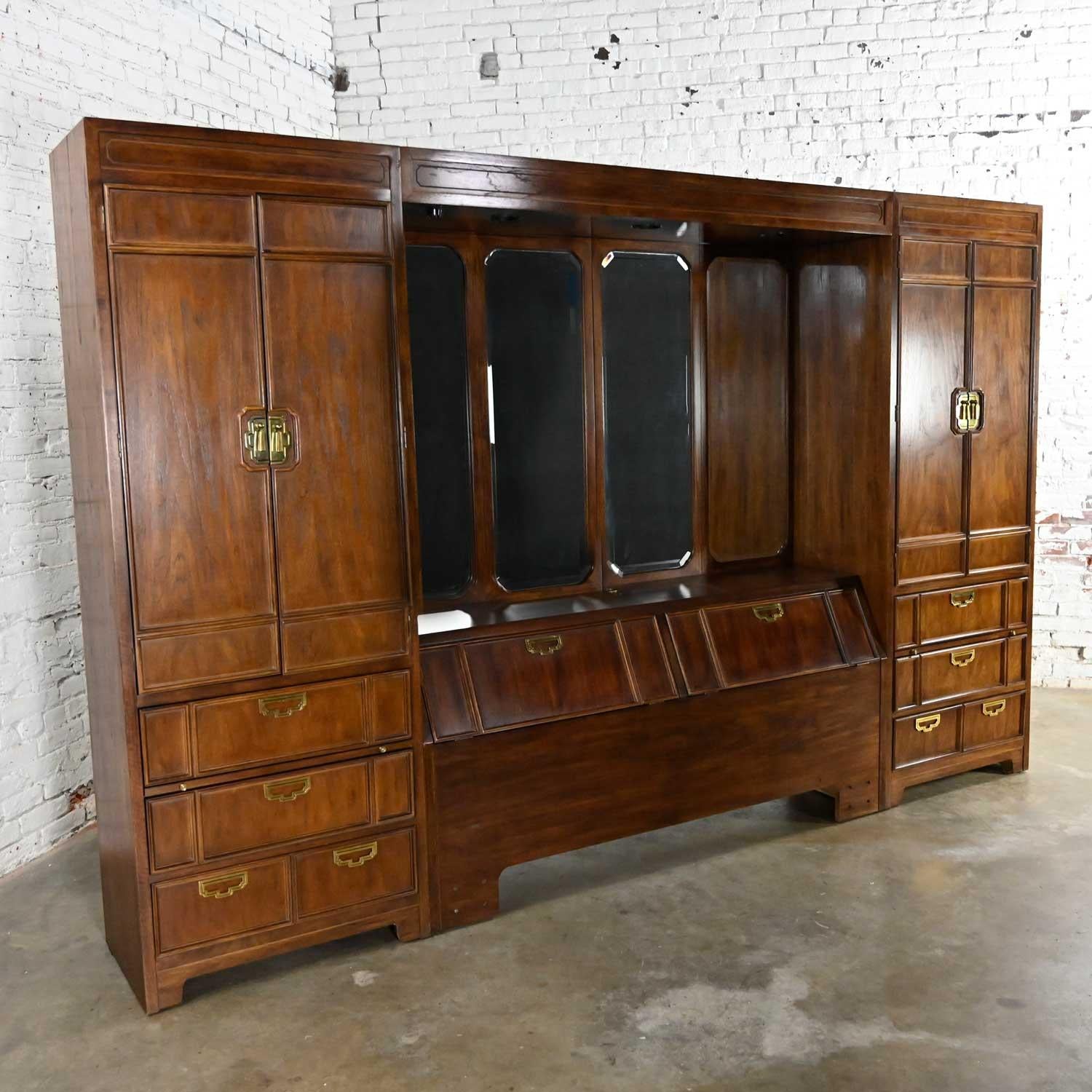 Wonderful campaign style modular wall unit bedroom or bed set up with side armoires comprised of dark wood, removeable mirrors, lights, full/queen headboard, and brass hardware by Thomasville Furniture. Beautiful condition, keeping in mind that this