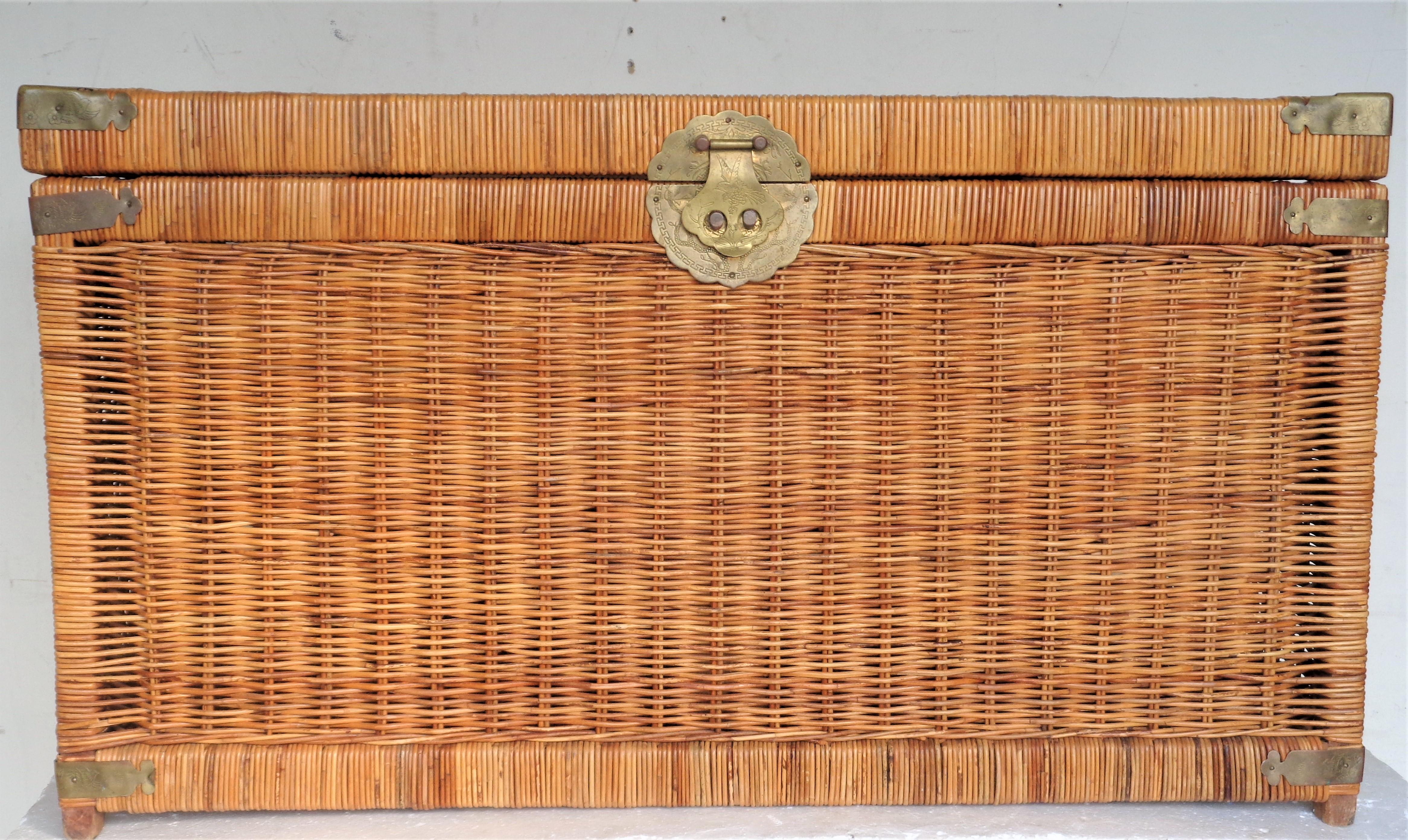 Campaign style wood frame woven natural wicker storage trunk in beautifully aged original honey colored surface with Asian motif decorated brass fittings / lock / side handles. The hinged top lid lifts to reveal a spacious open interior. Circa 1970.