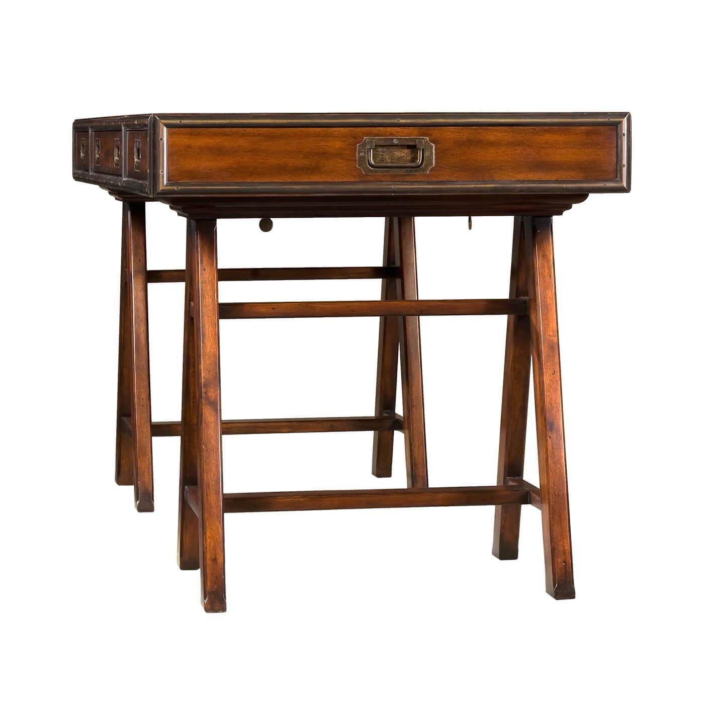 Campaign style writing table a brass bound writing table with three frieze drawers and raised on architectural-inspired trestle end bases. 

Dimensions: 60