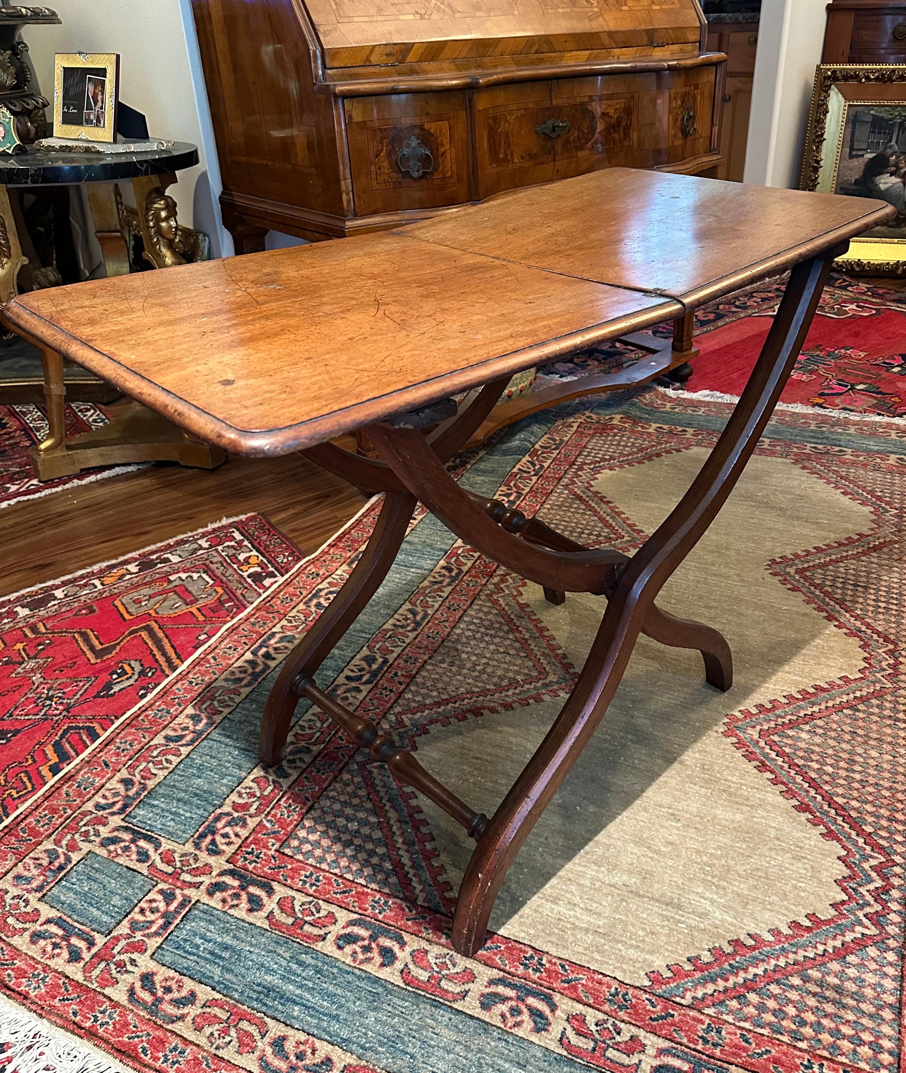 English 19th Century Victorian Campaign Folding Table.

Authentic folding Field Campaign table from England. The table has distinctive serpentine shaped legs in striking X-form with turned cross rails. The brass hinges and screws are from the