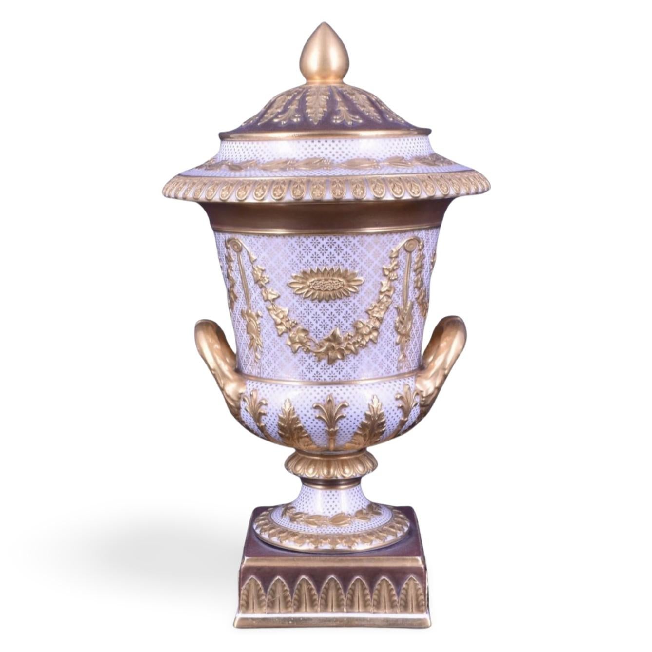 Un vaso campana in ceramica Victoria bianca e dorata. Lo stile è molto francese, la decorazione è una copia di quella di Sèvres. Funziona sorprendentemente bene con la forma neoclassica.