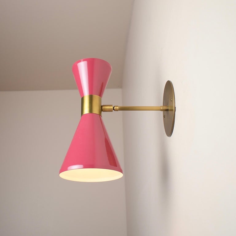 The Campana wall sconce or reading light shown in brushed brass and pink enamel by Blueprint Lighting, 2018. The wide band and distinctly bevelled edge makes the Campana a strong design statement. Swiveling head allows for cone adjustment. The spun