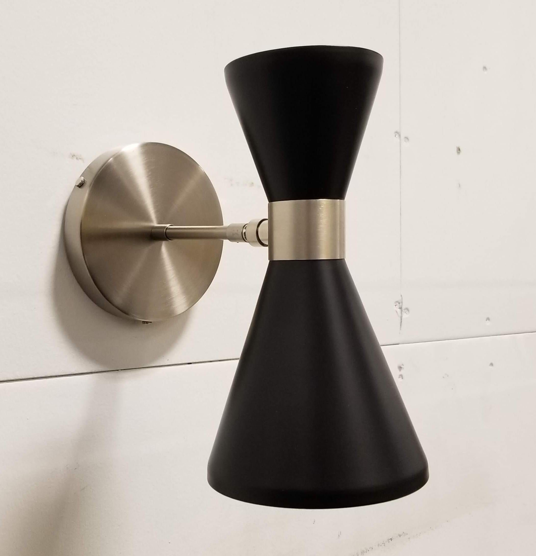 The Campana wall sconce or reading light shown in brushed nickel and matte black enamel fabricated in NYC by Blueprint Lighting, 2018. The wide band and distinctly bevelled edge makes the Campana a strong design statement. Swiveling head allows for