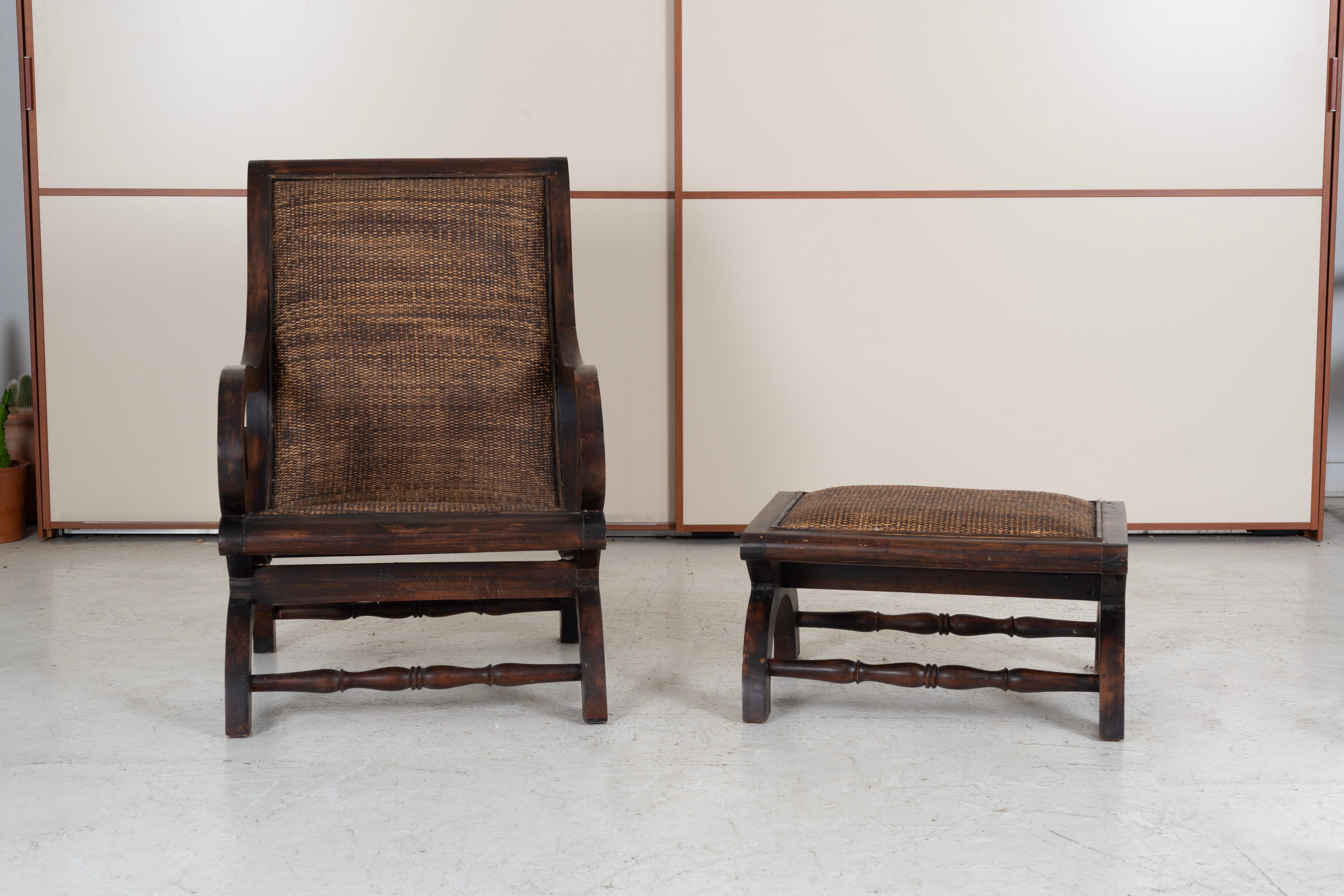 Anglo-Indian plantation lounge chair and ottoman, made in the Grand British Colonial style. The chairs features large scrolled arms with caned seat and ottoman. The chairs have a desirable weathered patina on the finish.

Ottoman Dimensions
H: