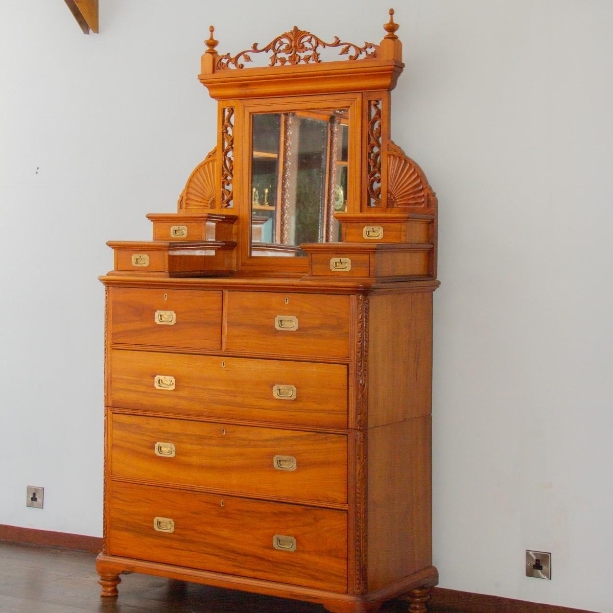 A camphor wood campaign dressing chest with five deep drawers furnished with brass recessed handles. Atop the chest are four small stepped drawer and a mirror with carved fans and foliage fretwork. This campaign chest is fairly unusual as they