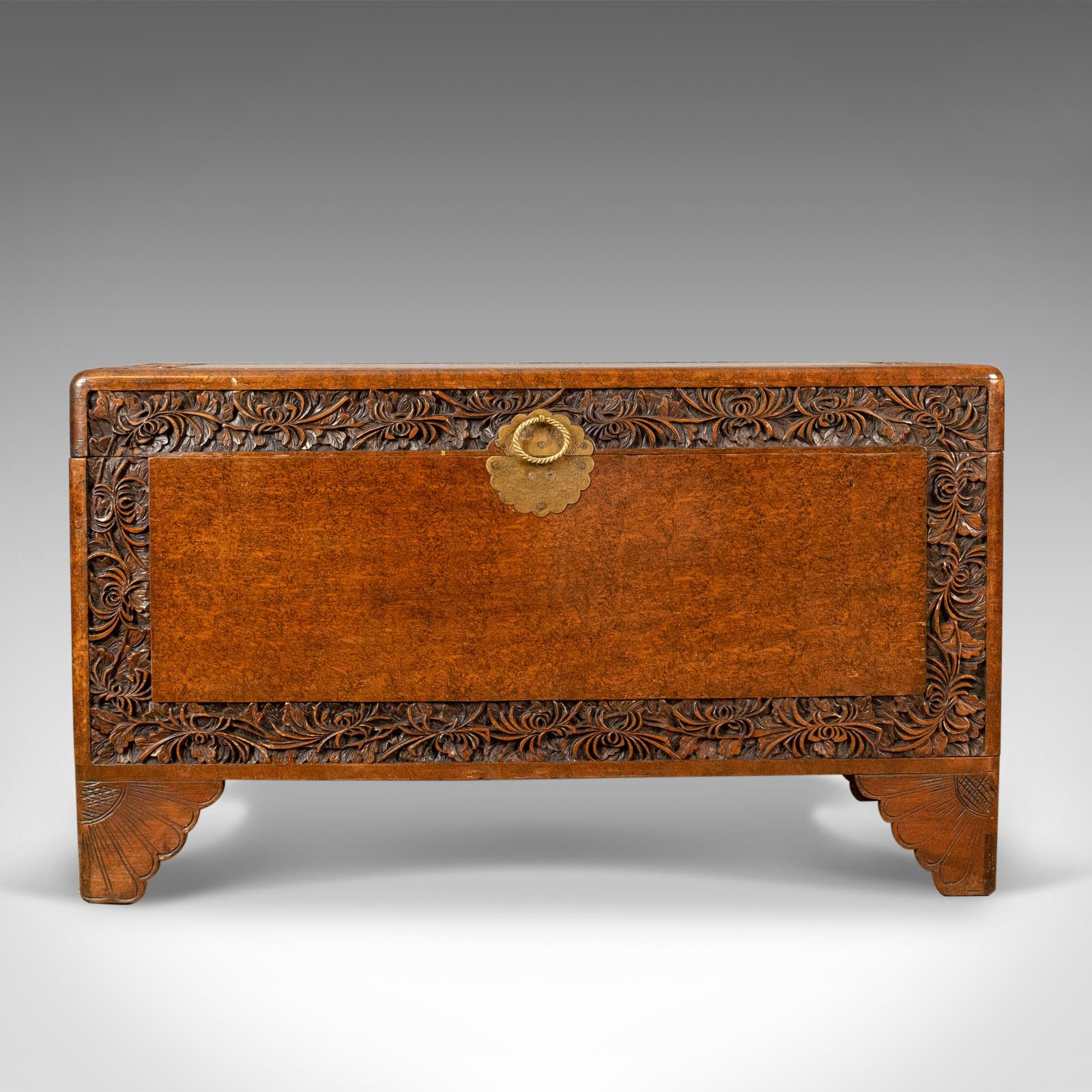 This is a camphor wood trunk, an oriental, carved chest dating to the late Art Deco period, circa 1940.

Of quality craftsmanship and stock
Attractive grain interest in warm russet hues
Solidly constructed with brass handle and etched back