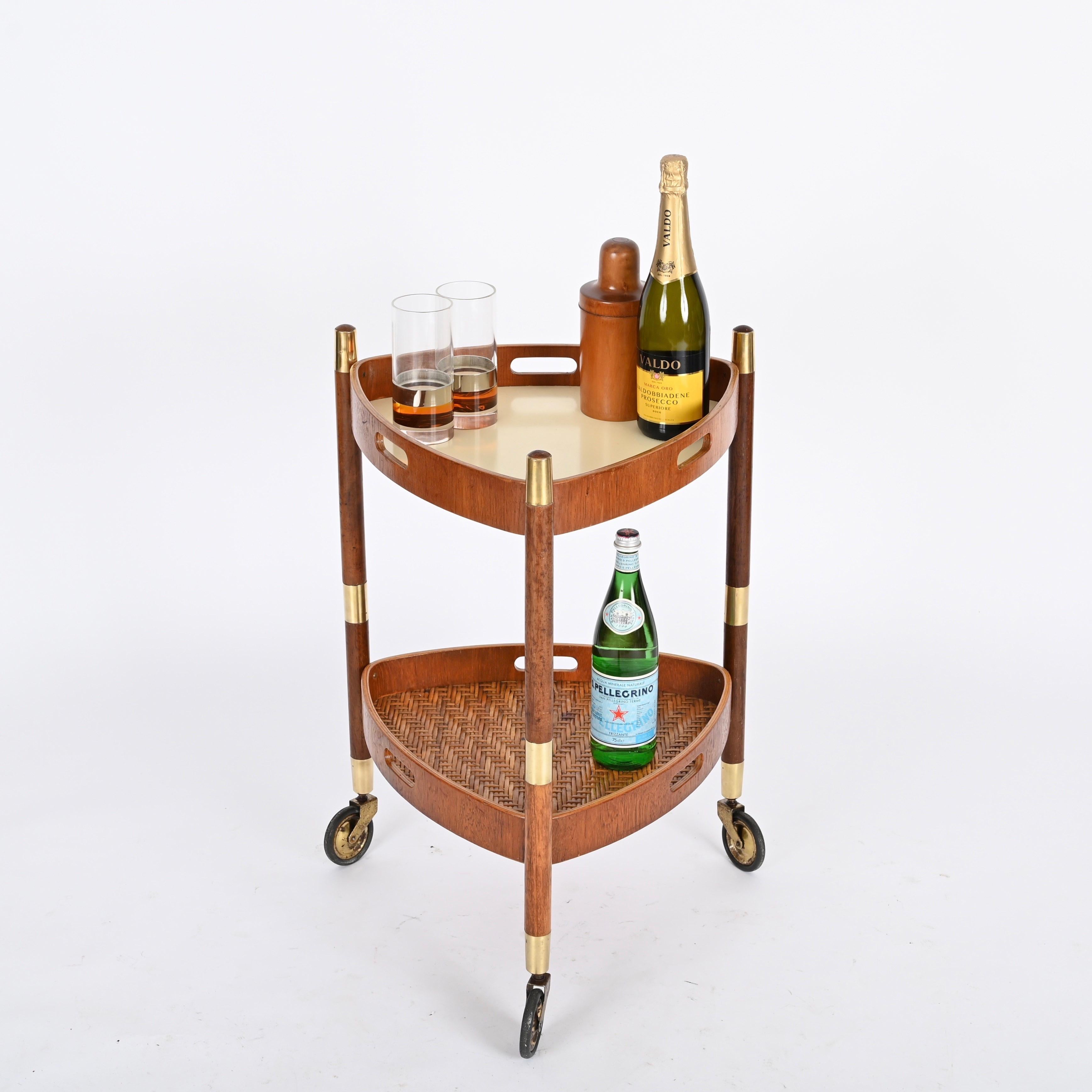 Gorgeous triangular shaped serving bar cart with removable top tray in a beautiful combination of teak wood, brass, hand-woven wicker and white laminate. This incredibly unique and elegant piece was designed by Campo & Graffi and produced in Italy