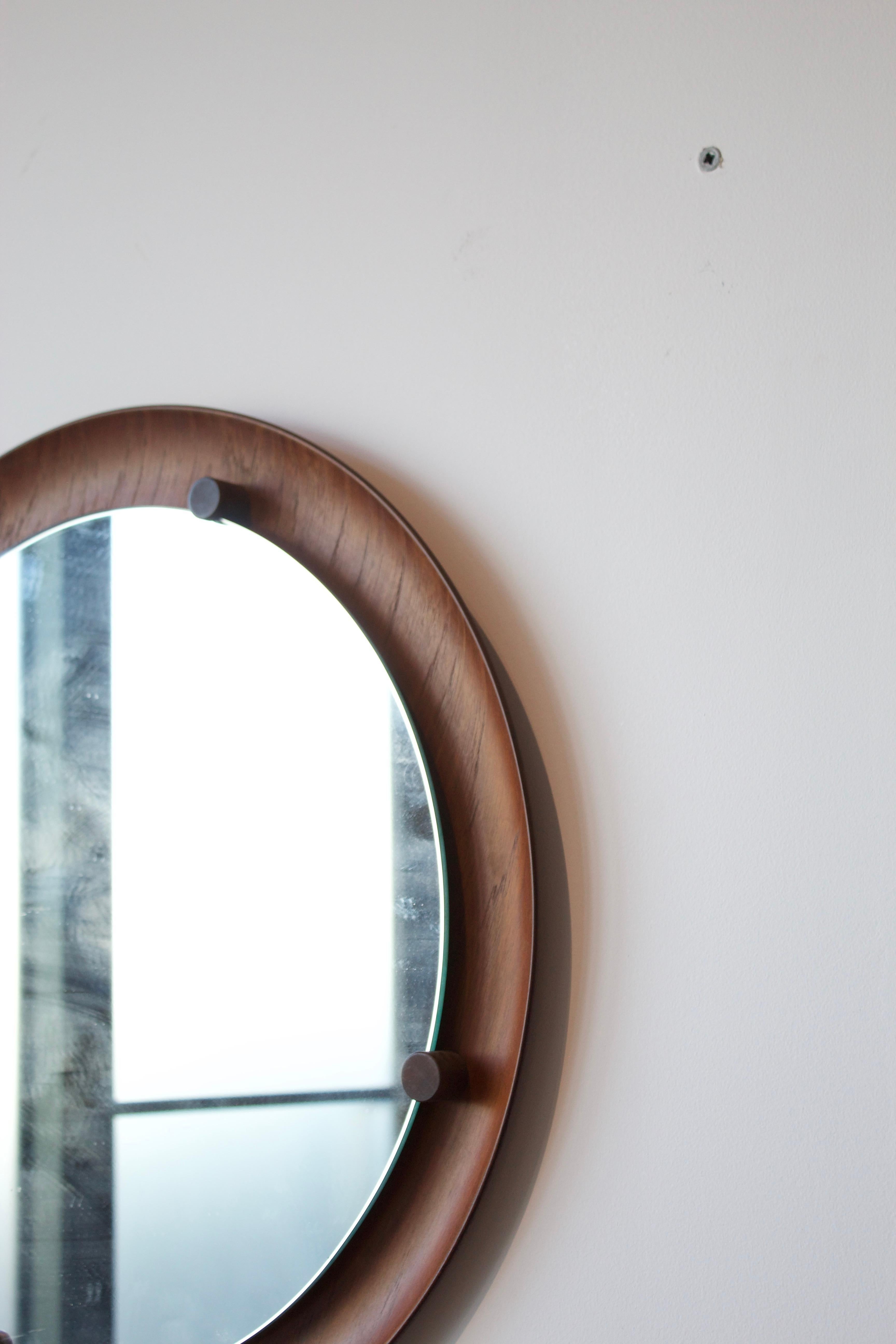 A wall mirror, design attributed to Franco Campo and Carlo Graffi, presumably manufactured by Home, Italy, 1950s-1960s.

In teak plywood and original cristal glass.