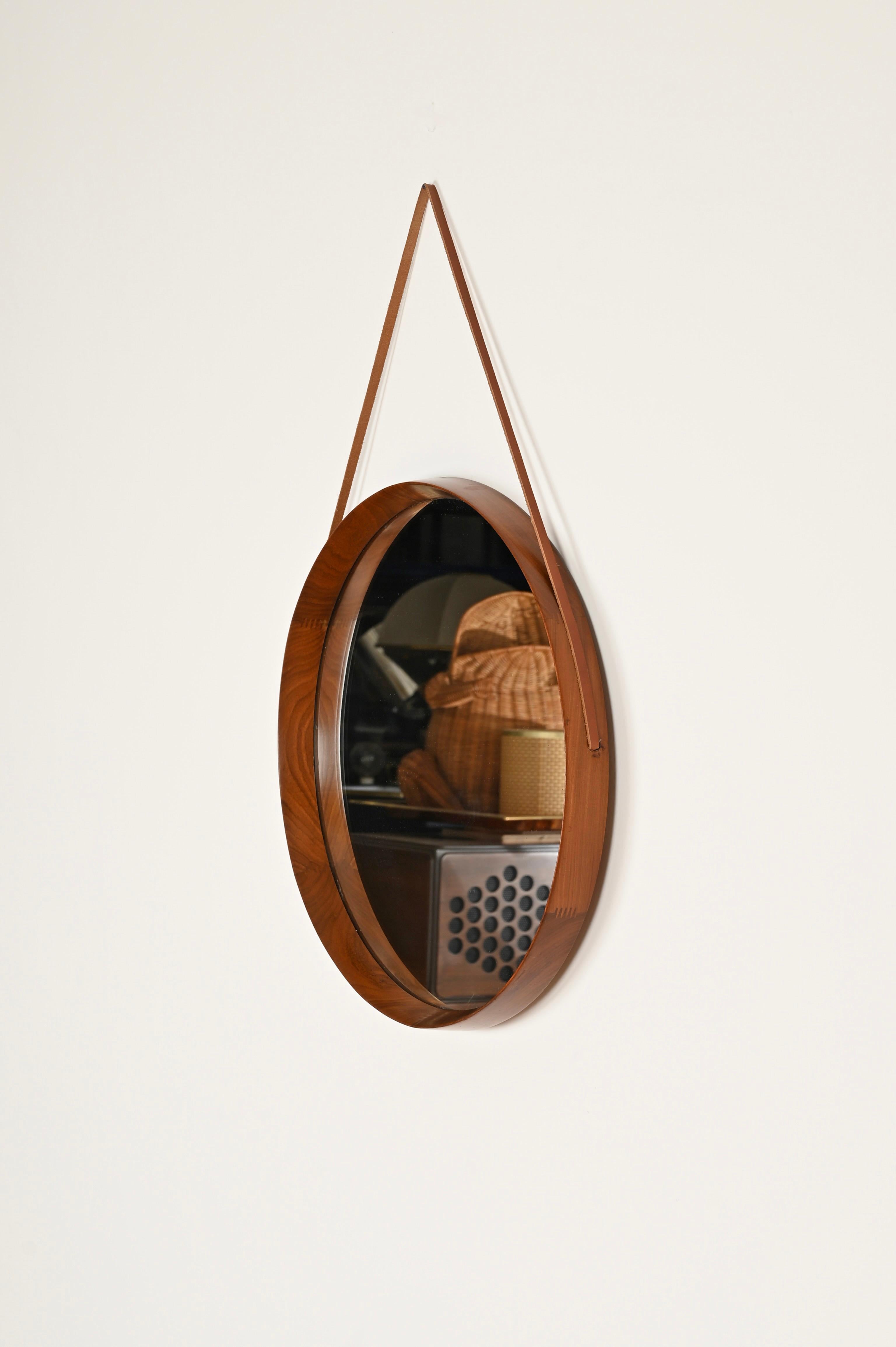 Stunning Mid-Century round mirror in a beautiful flame walnut and leather. This gorgeous mirror was designed by Campo and Graffi and produced by Mobili Cantu in Italy during the 1960s. The mirror is signed on the back. 

Fully original and in