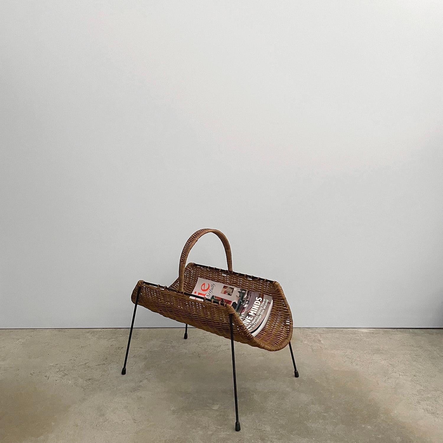 Campo Graffi wicker and iron magazine rack
Italy, 1950s 
Intricately woven wicker encompasses sculpted iron frame 
Handwoven wrapped arch handle 
Natural color variations 
Patina from age and use 
Perfect for magazine and book storage as well as a