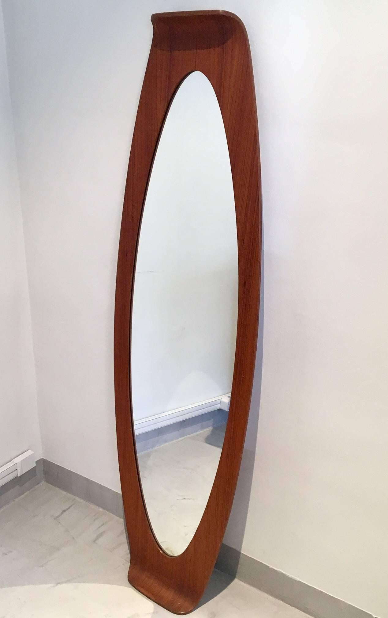Large oval mirror from the 1960s designed by Franco Campo & Carlo Graffi for Home, Italy. Bent plywood frame. 
Slight discoloration on the bottom of the mirrored glass and minor stains on the frame.
