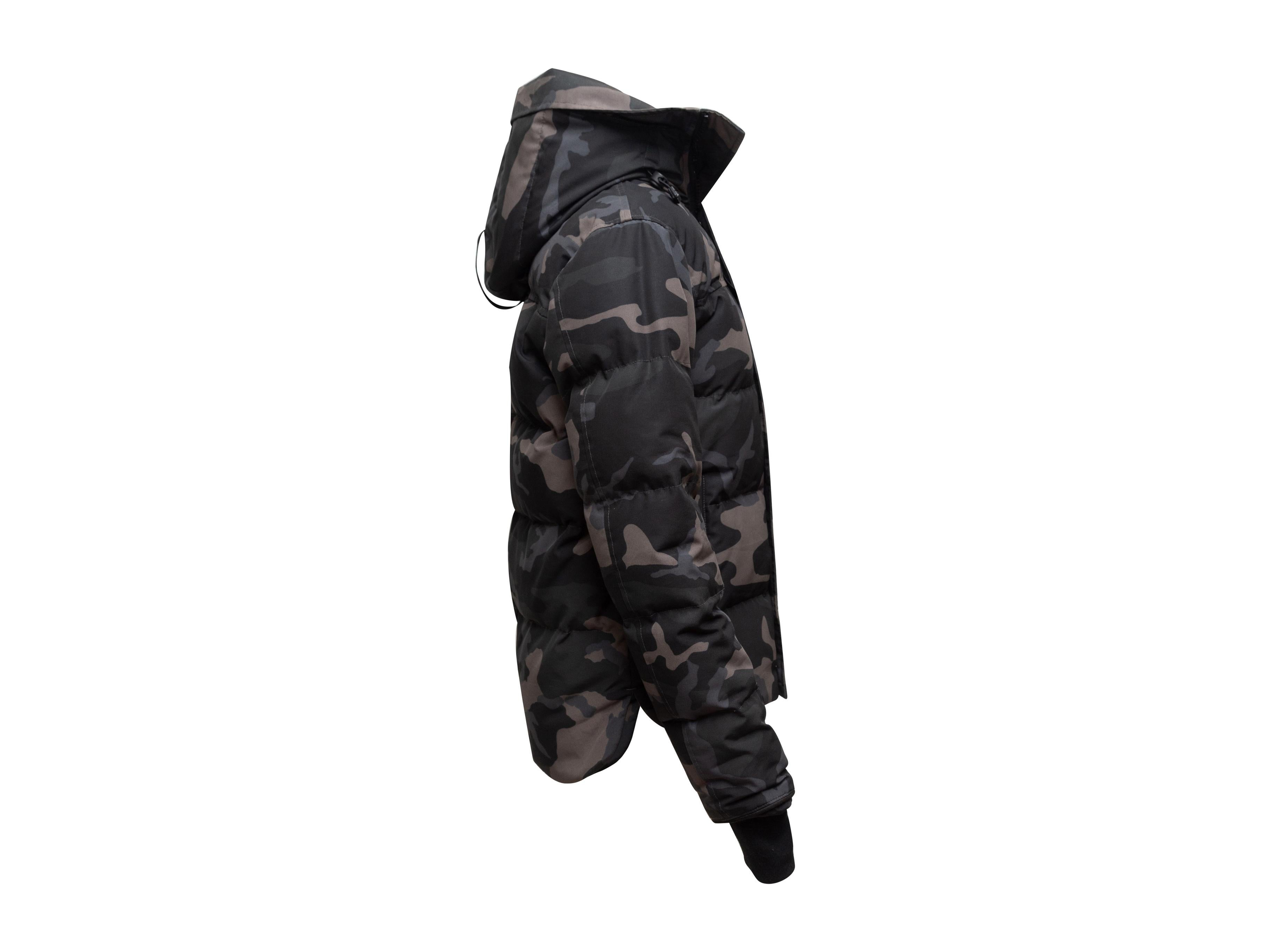 Product details: Grey and black hooded down puffer jacket by Canada Goose. Camo print throughout. Dual hip pockets. Concealed zip closure at front. 32