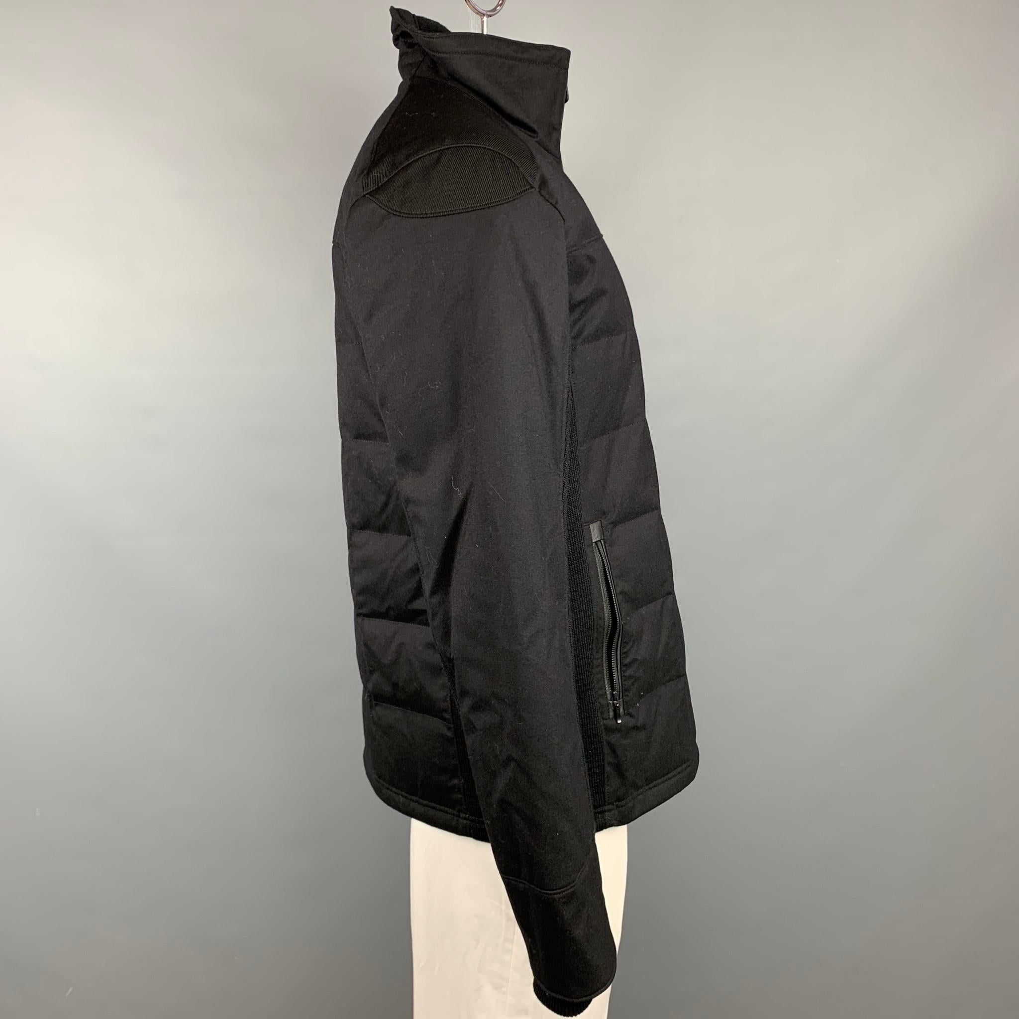 CANADA GOOSE jacket comes in a black wool with ribbed sides featuring a high collar, zipper pockets, and  a full zip up closure. Made in Canada.

Very Good Pre-Owned Condition.
Marked: XL

Measurements:

Shoulder: 20 in.
Chest: 44 in.
Sleeve: 28