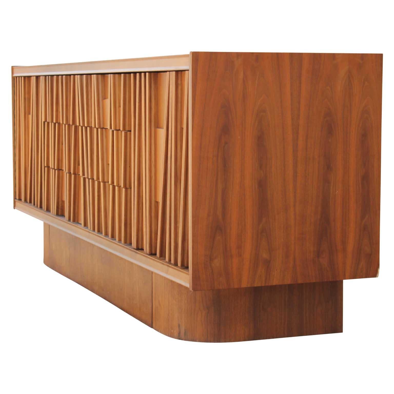 Stunning Brutalist credenza. It has three drawers and two cabinet spaces with magnetic closures for storage. The front has a linear mosaic wood design that camouflages the drawers and doors. There are no makers marks.

      