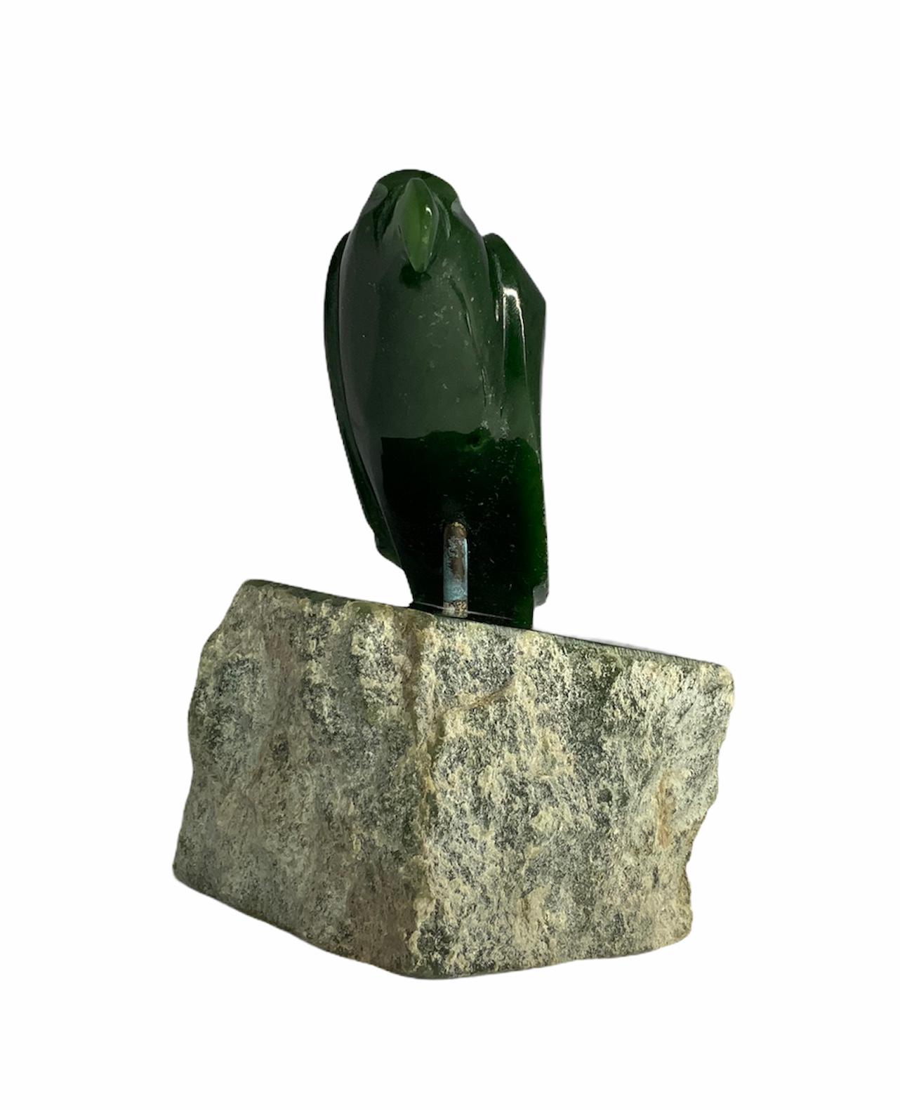 This is a finely carved Canadian Jade stone depicting a raven standing over a crude Jade rock.