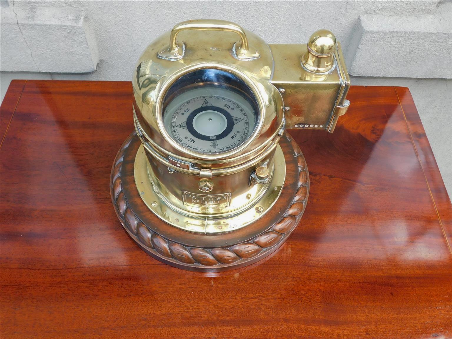 Canadian Nautical brass yacht binnacle mounted on a mahogany rope base with an oval glass viewing port, gimballed compass, central carrying handle, and the original brass side light with interior font, 20th Century.
Binnacle is fitted with an