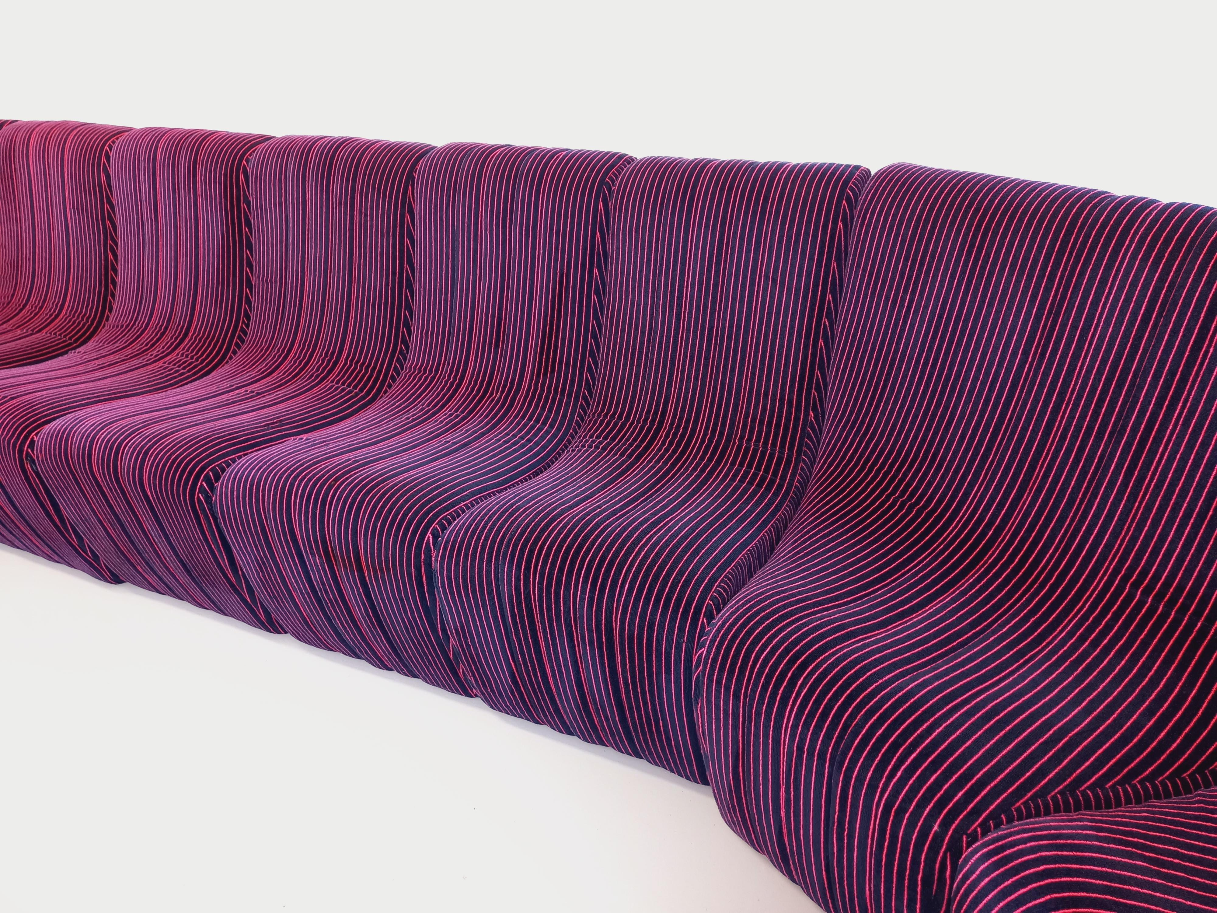 Incroyable et immense canapé banquette entièrement modulable vintage des années 70 80, modèle Snake, composé de 11 modules d’assises type chauffeuses et de 3 poufs repose-pieds, en tissu velours bleu foncé avec fines rayures rose fushia, pour un