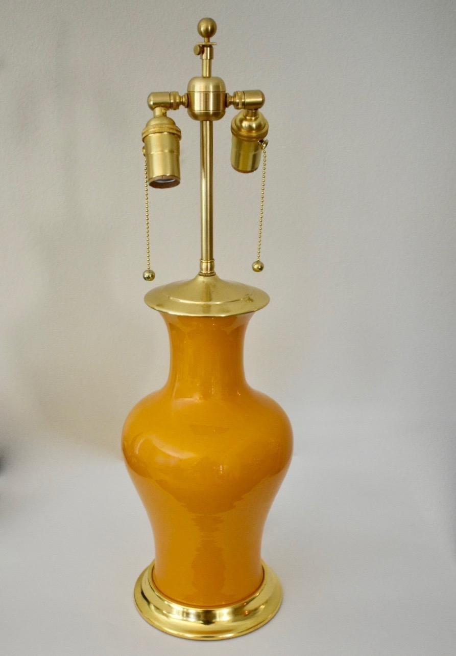 Fishtail form mid-20th century Chinese export porcelain vase converted to a lamp on custom 23-karat water gilt turned wood base. Porcelain is a glossy canary yellow glaze. Brass double cluster pull chain sockets and brass fittings. Newly wired for
