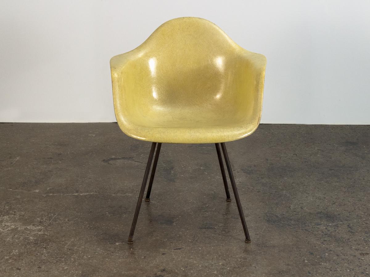 Canary yellow molded fiberglass armchair on original black lounge base, designed by Charles and Ray Eames for Herman Miller. Ours is a first edition with the desirable rope-edge detail. Distinct thread texture throughout surface with a very nice