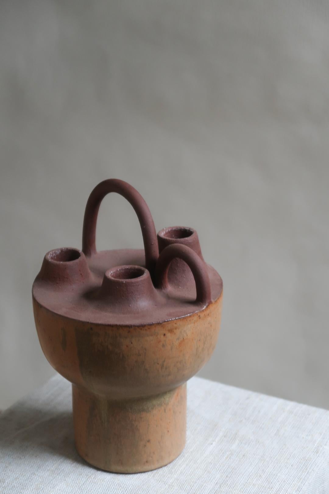 Candelabro 001 di Studio A Tsang
Dimensioni: L 13 x H 20 cm.
Materiali: Gres di colore scuro con finitura opaca, parzialmente smaltato.

Tutto è iniziato con una semplice tazza di caffè. Una forma arrotondata, realizzata a mano e progettata per